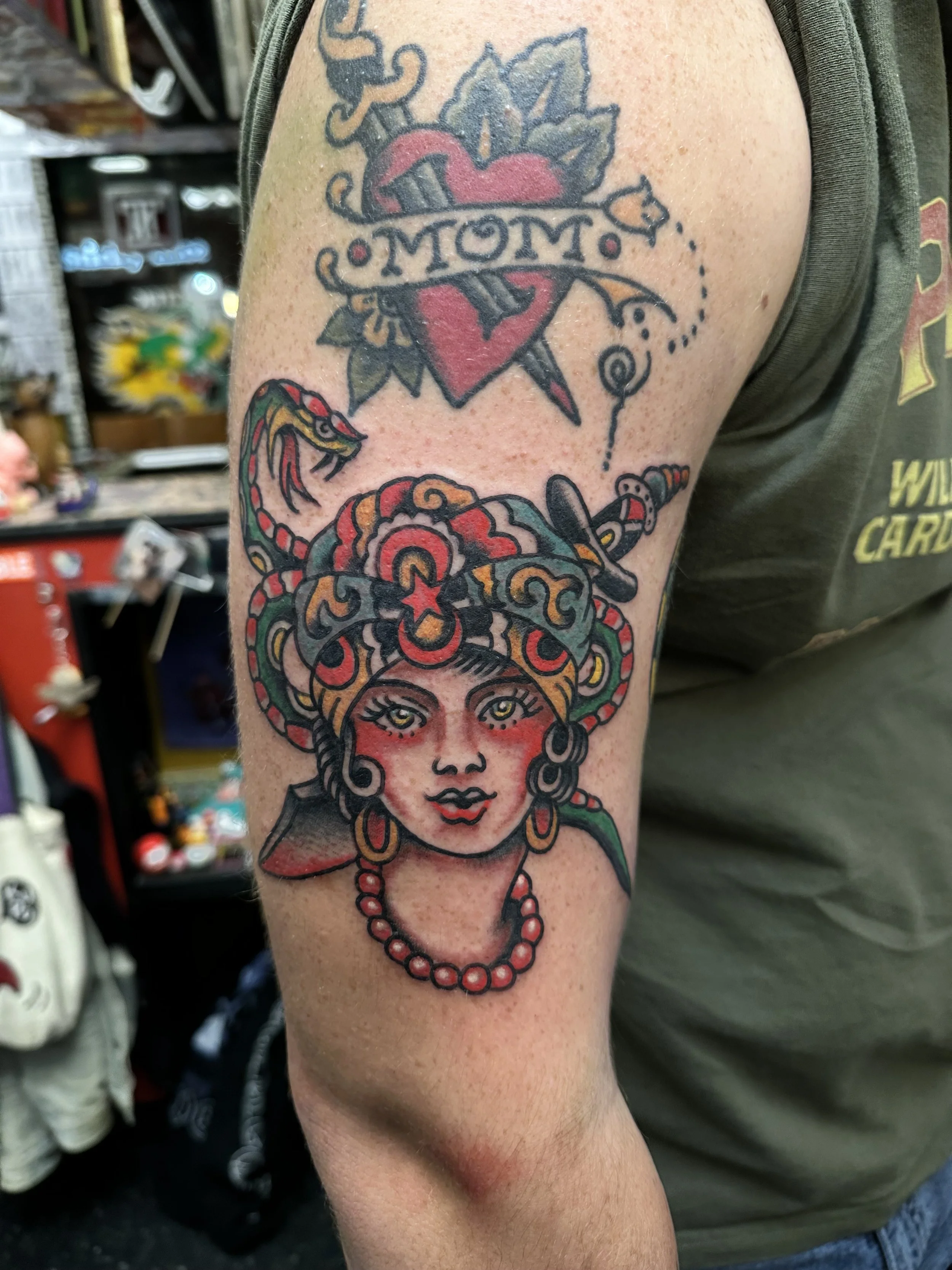 Tattoo of a woman's face with colorful hair, earrings, and a red necklace on an arm.