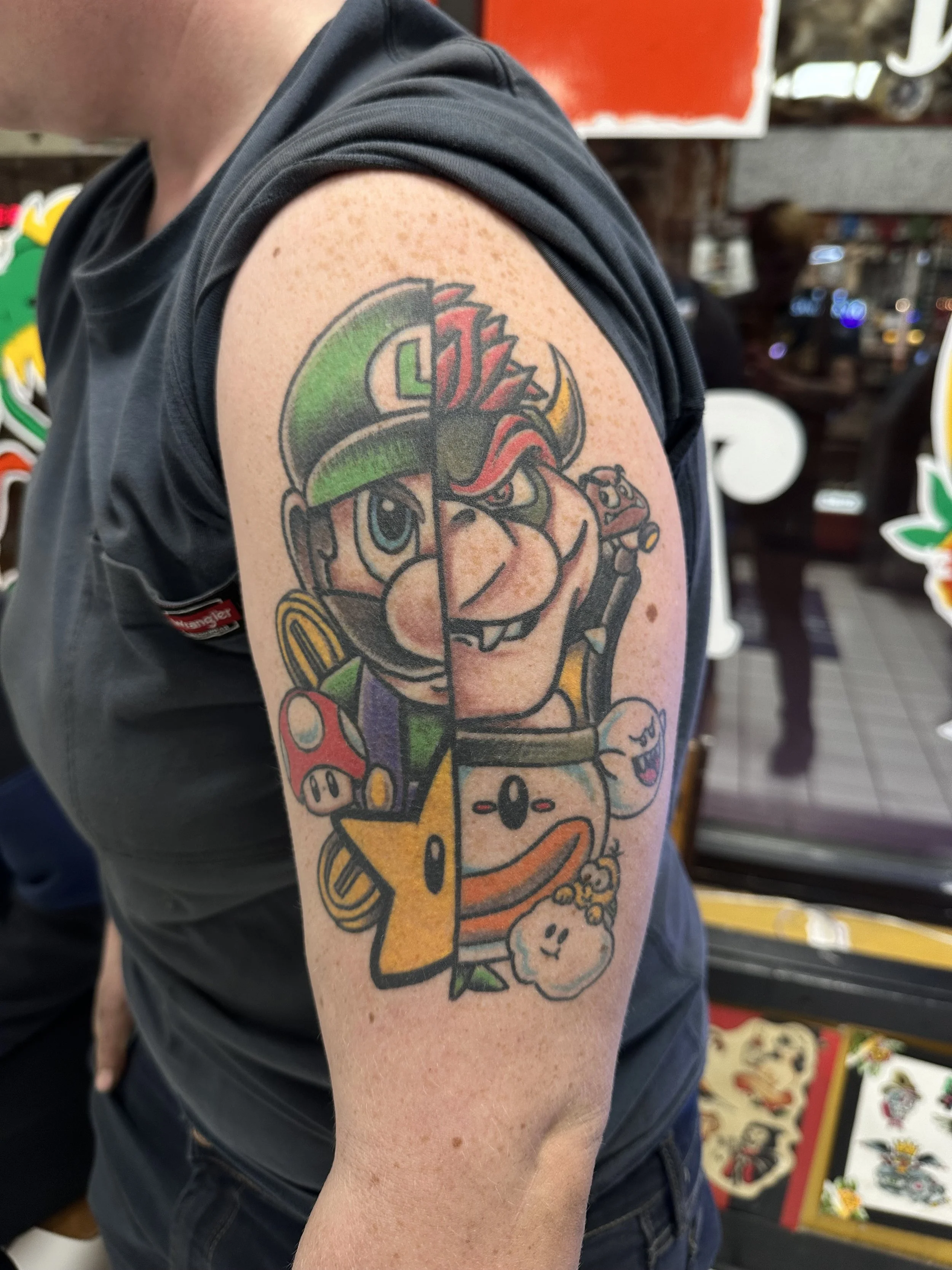Tattoo on person's upper arm of a cartoon chef with a Landshark beer, surrounded by various small colorful cartoon characters.