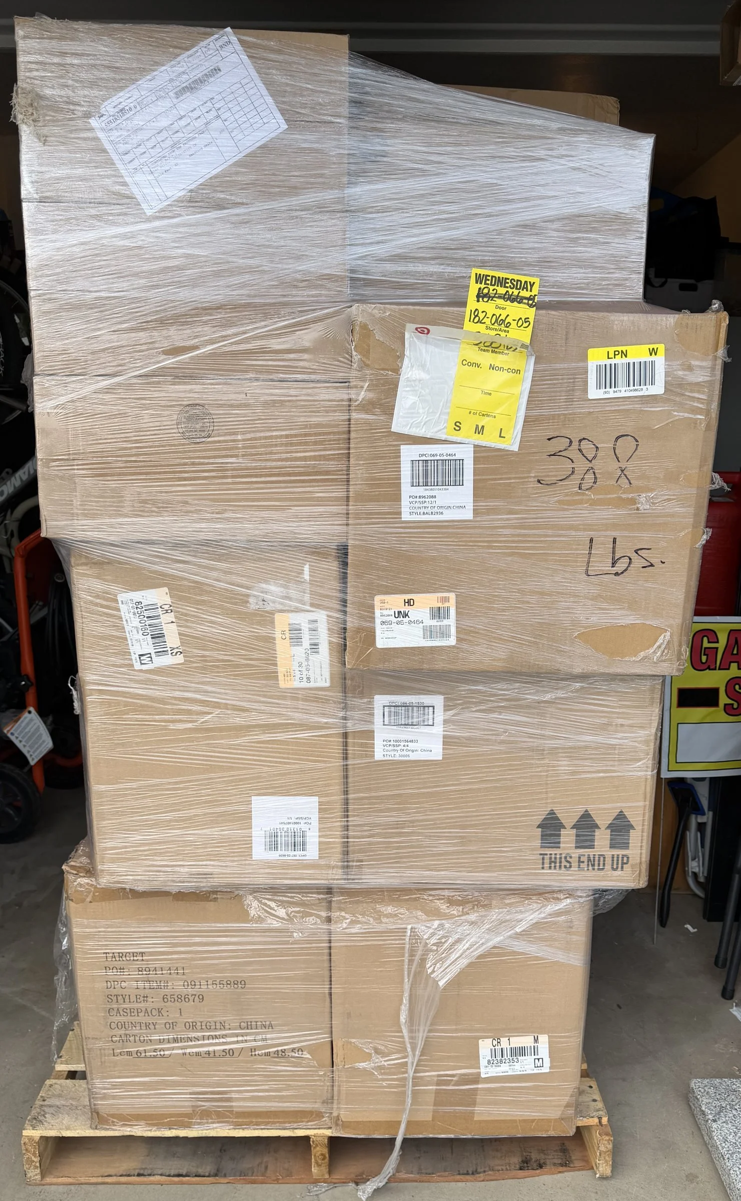 A large pallet of overstock Target toys wrapped in plastic wrap, with shipping labels and handwritten markings, placed on a wooden pallet in a warehouse.
