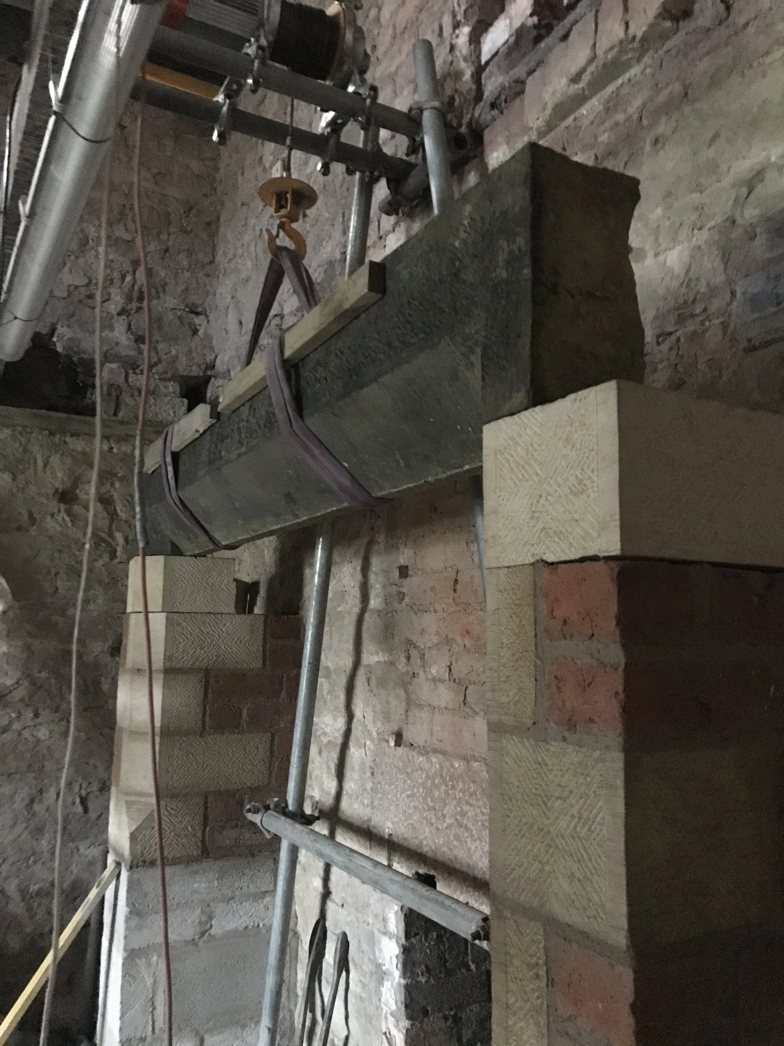Construction site with brick walls, metal pipes, and scaffolding in an indoor setting.