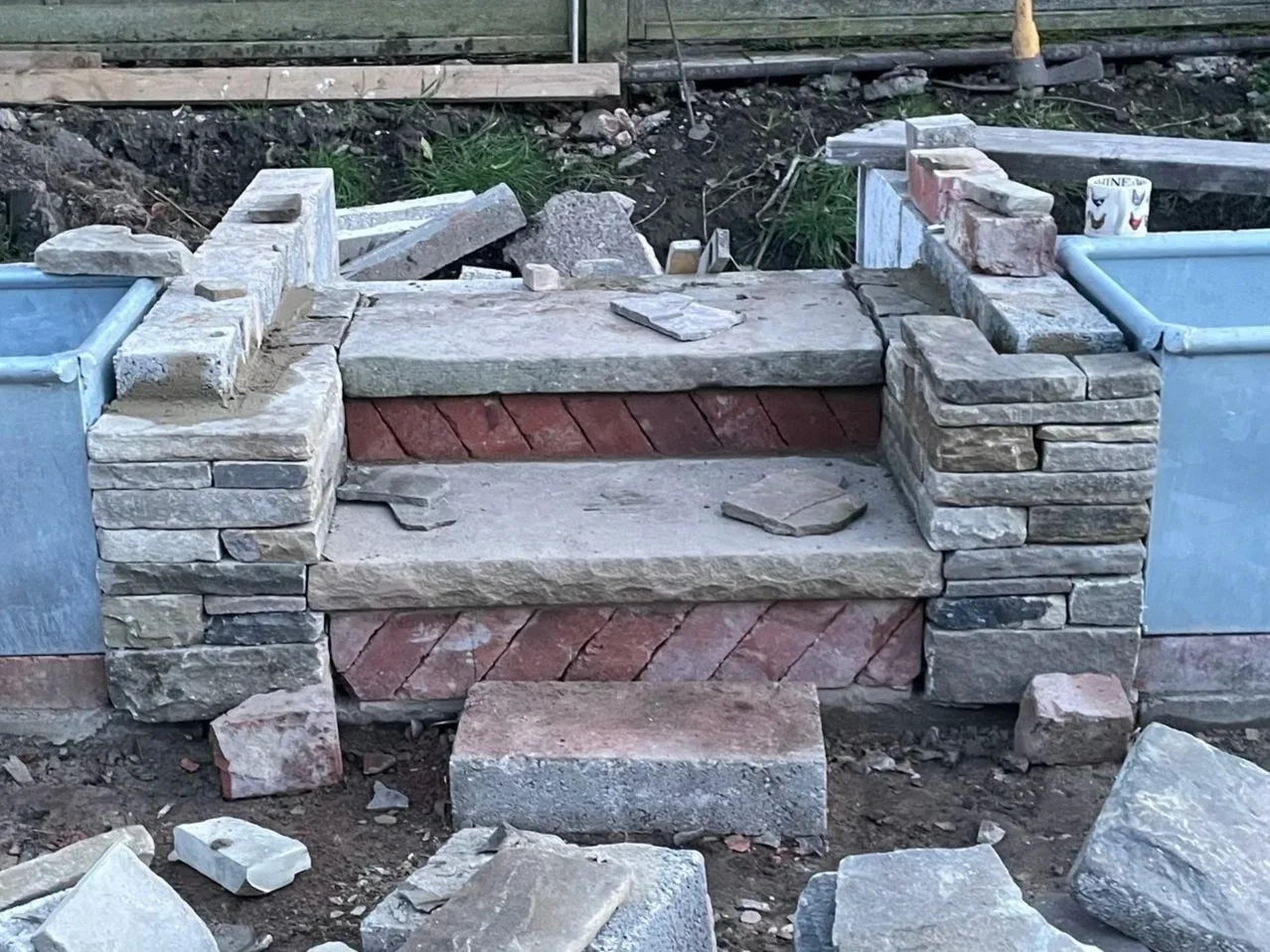 Constructed stone steps made of bricks and large stones in an outdoor area with construction materials around.