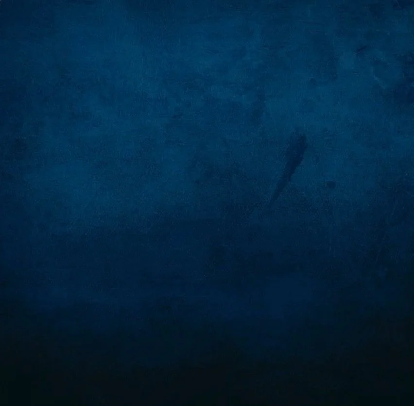 A close-up of a dark blue surface with a small, faint scratch or mark.