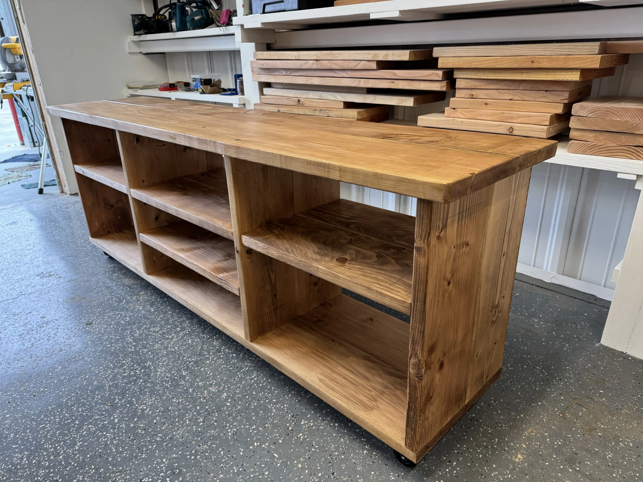 A wooden display shelf with multiple compartments in a workshop or garage setting.