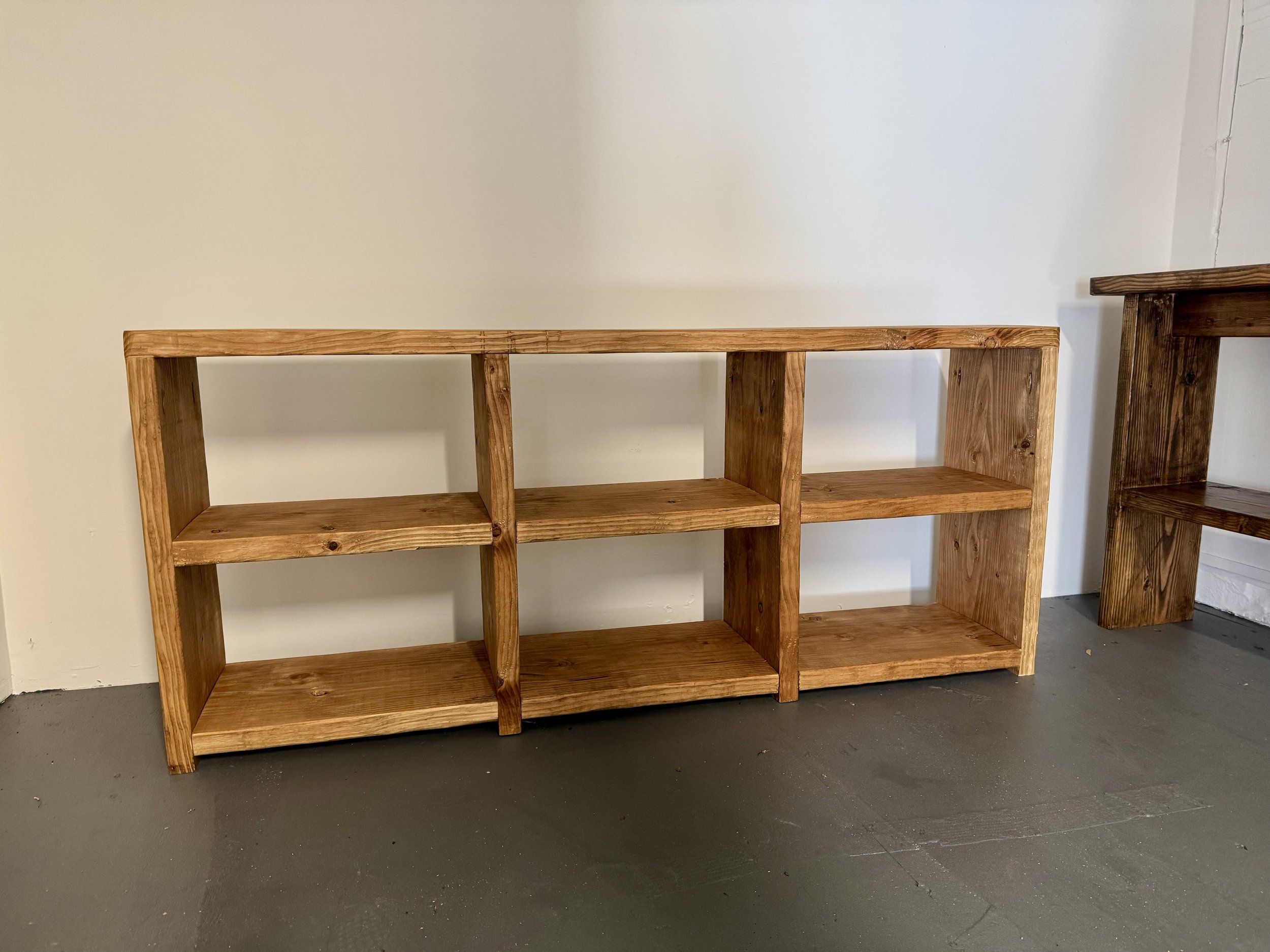 Wooden bookshelf with three shelves against a white wall.