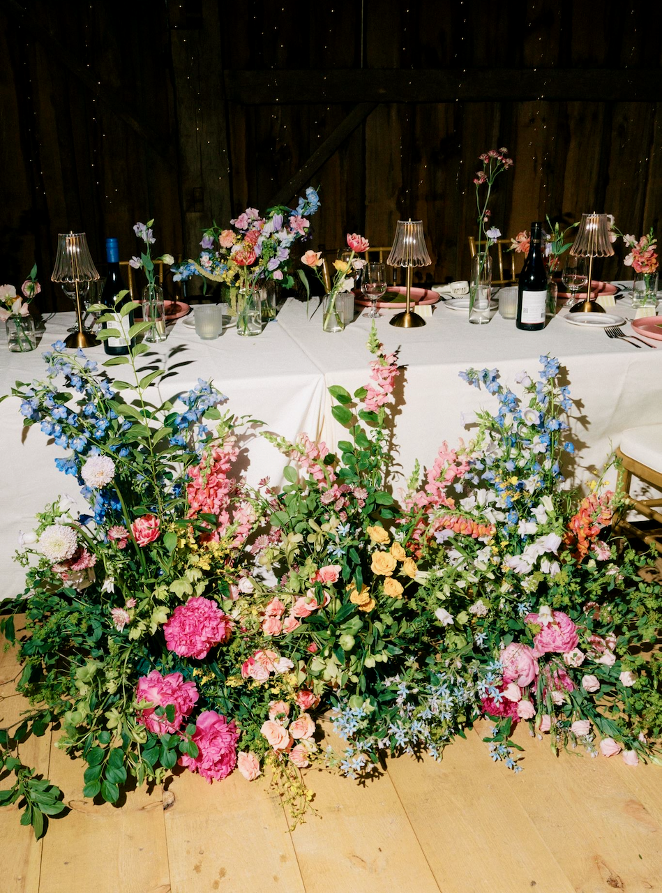 A decorated dining table with floral centerpieces and tableware in a rustic setting with wooden walls.