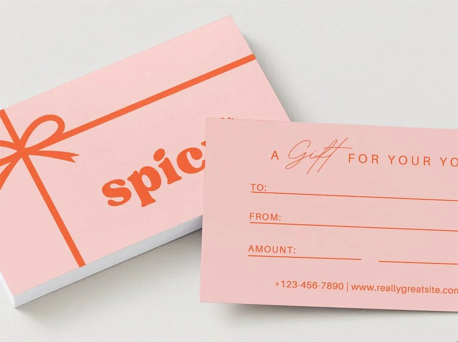 Pink gift card box with the word 'spice' and an orange ribbon graphic, and a pink gift card with spaces for recipient, sender, and amount, with contact information.