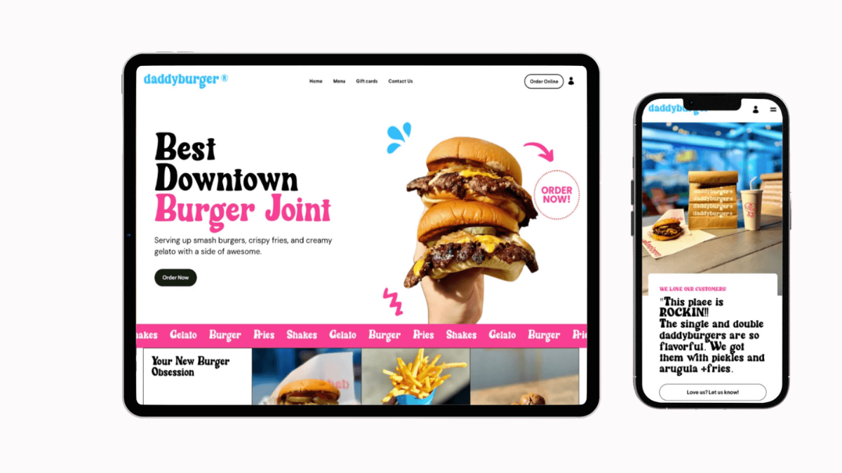 A laptop and a smartphone showing a burger restaurant's website. The laptop screen displays a large image of a person holding a triple burger, with menu options and colorful text. The smartphone screen shows a smaller burger with a background of table and chairs, and a customer review.