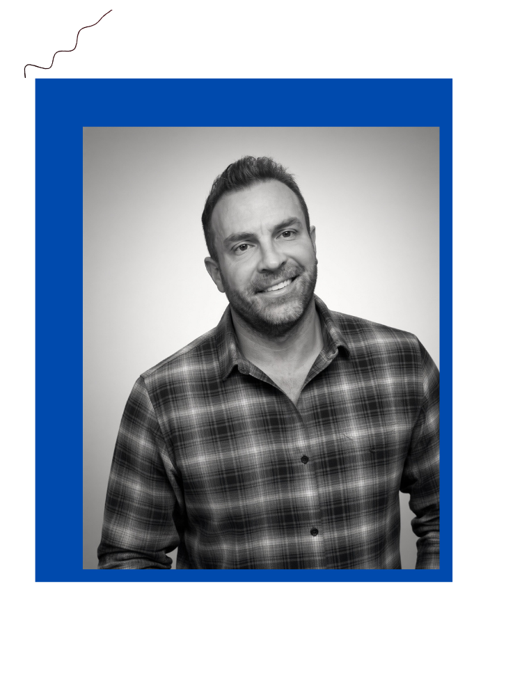 Black and white portrait of a smiling man wearing a plaid shirt