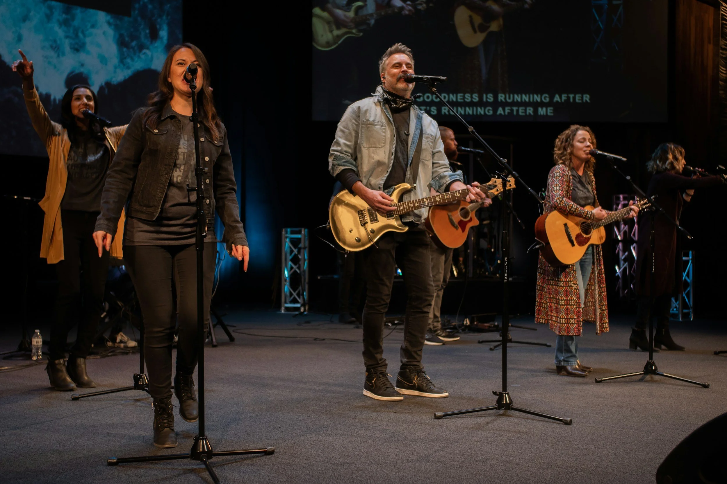 Worship leaders leading a congregation on stage.