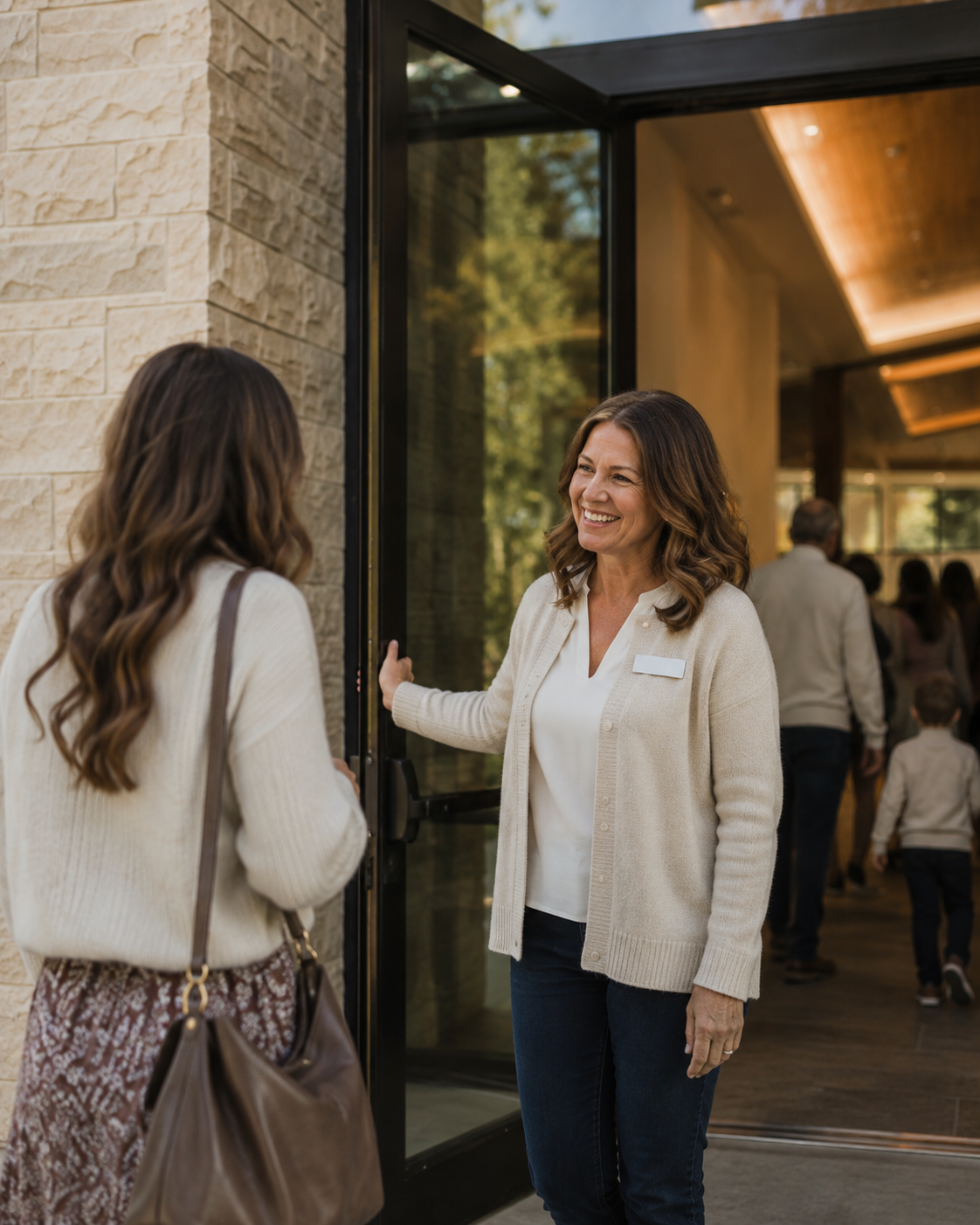 A woman welcoming a guest to church by holding the door and smiling.