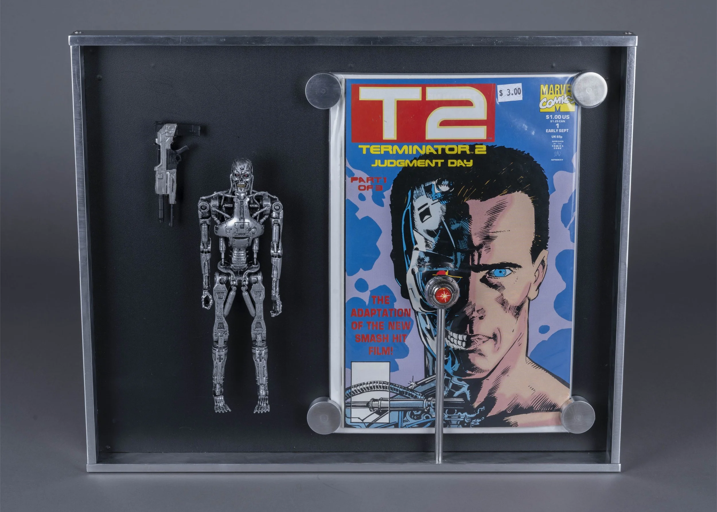 A pinball machine featuring a metallic robot figure on the left and a poster for the movie "Terminator 2: Judgment Day" on the right. The poster shows a close-up of a man's face with part of a robotic eye visible, and the text "The adaptation of the new smash hit film." The robot figure appears to be a T-800 terminator model.
