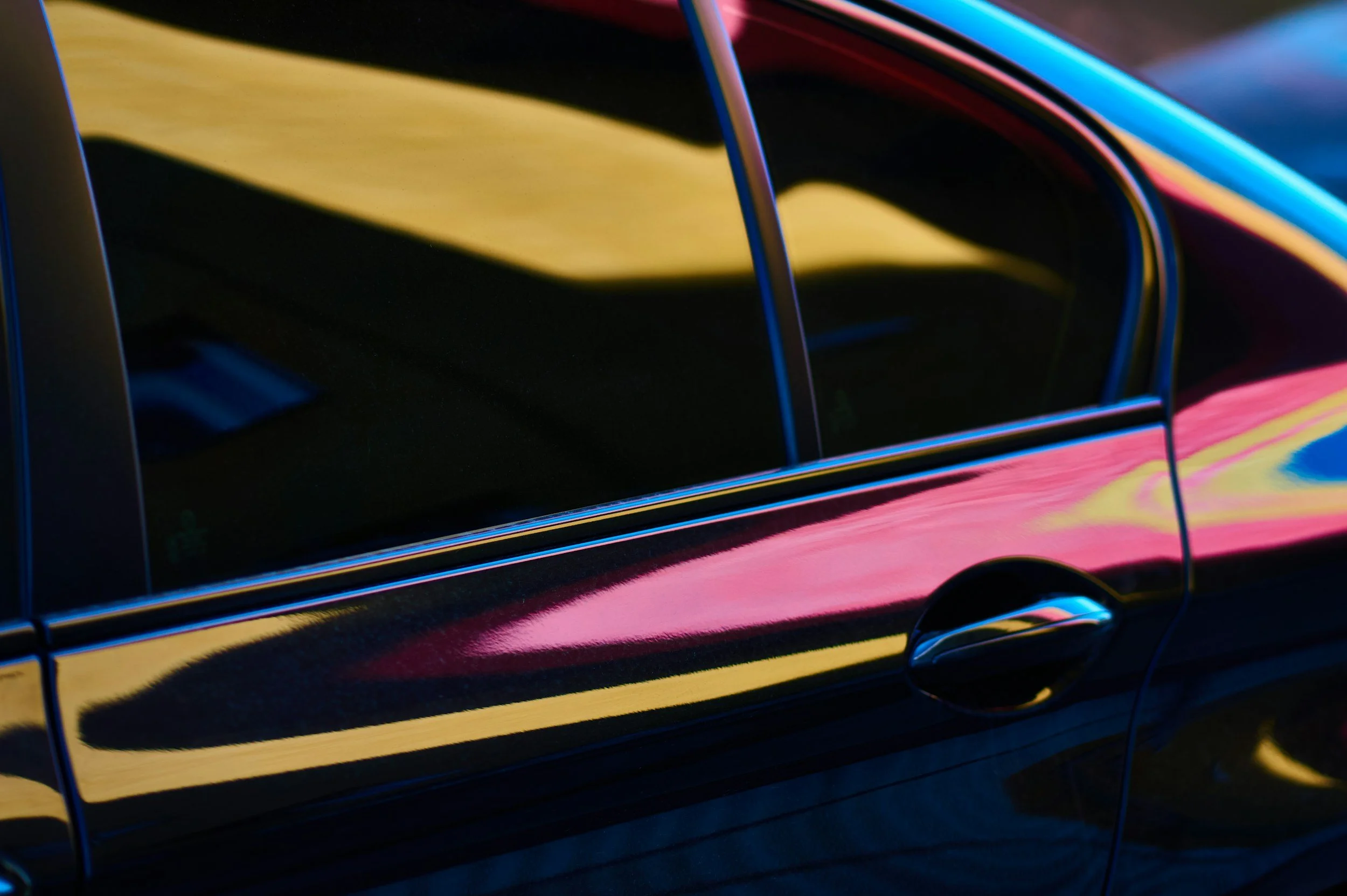 Close-up of a multicolored car with reflections on its surface.