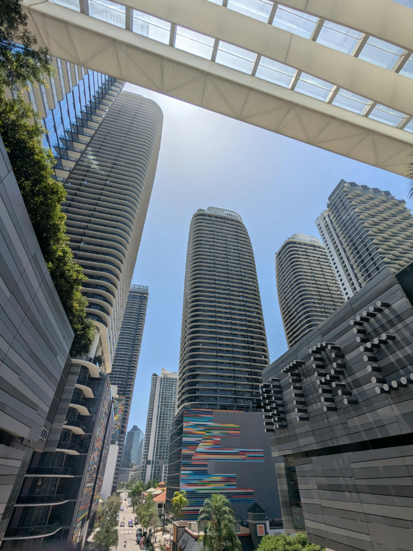 Skyline view of tall modern skyscrapers in Brickell, Miami, with blue sky and a few scattered clouds.