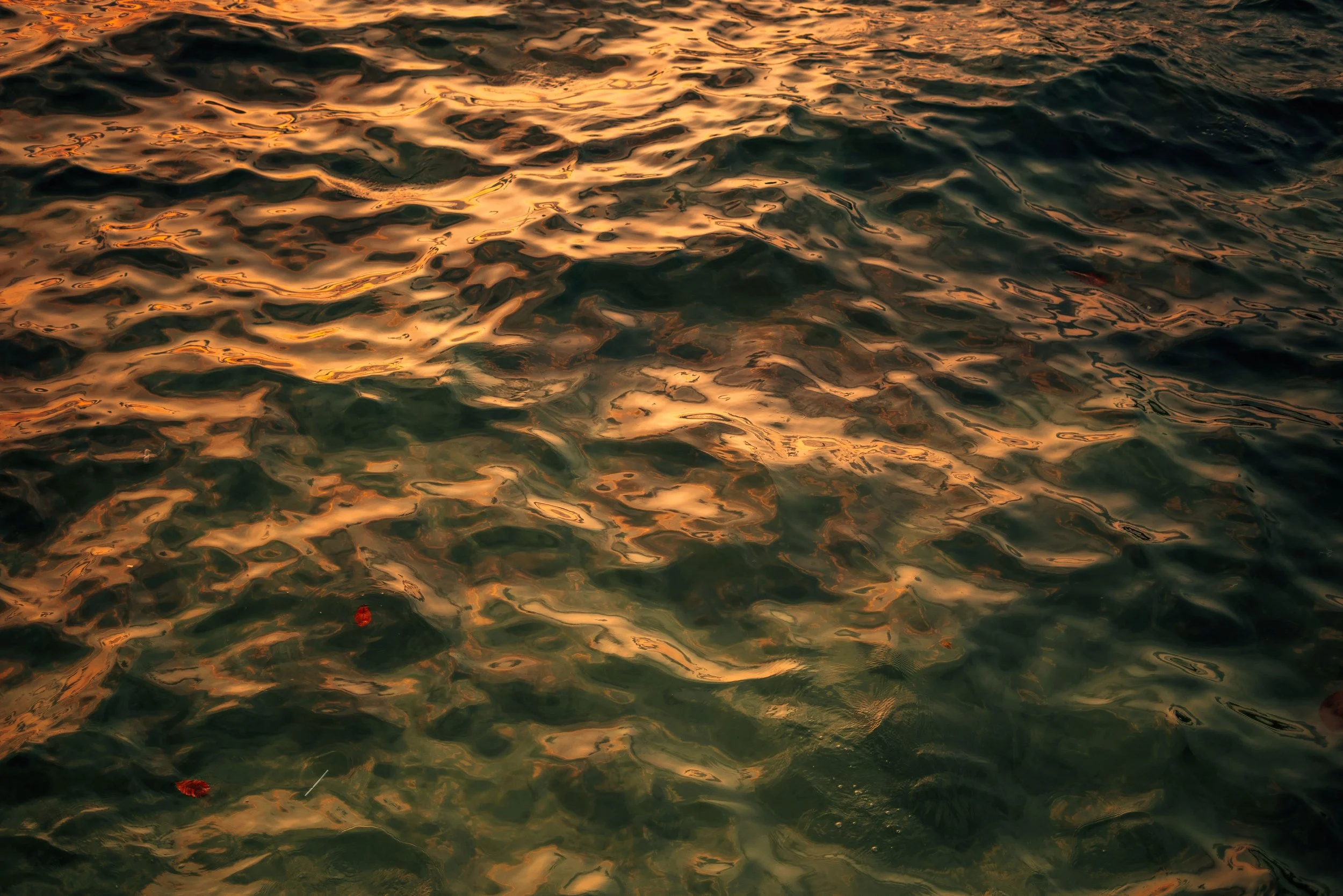 Sunset reflection on water surface with ripples and warm orange glow.