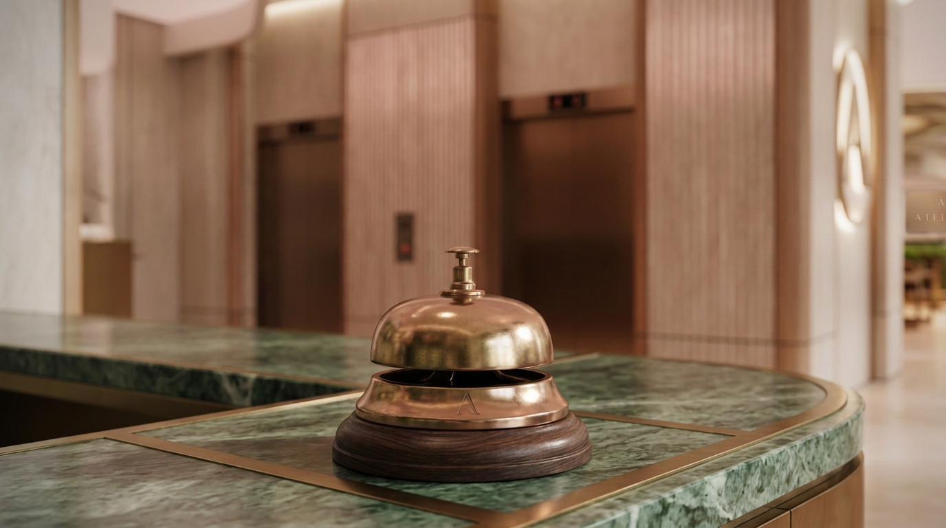 A brass hotel reception bell on a green marble counter in a hotel lobby.