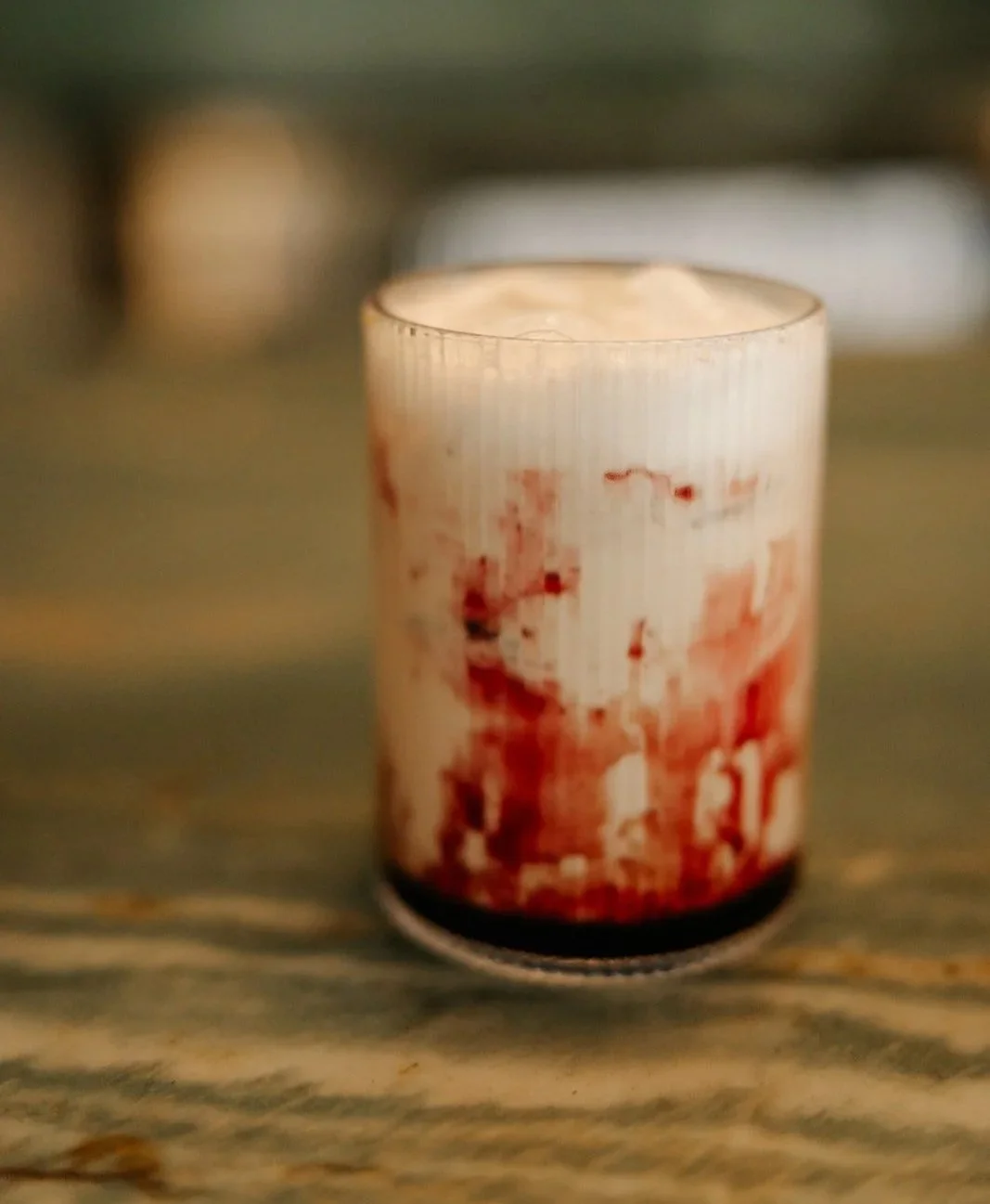 A candle with a red and white design on a wooden surface.