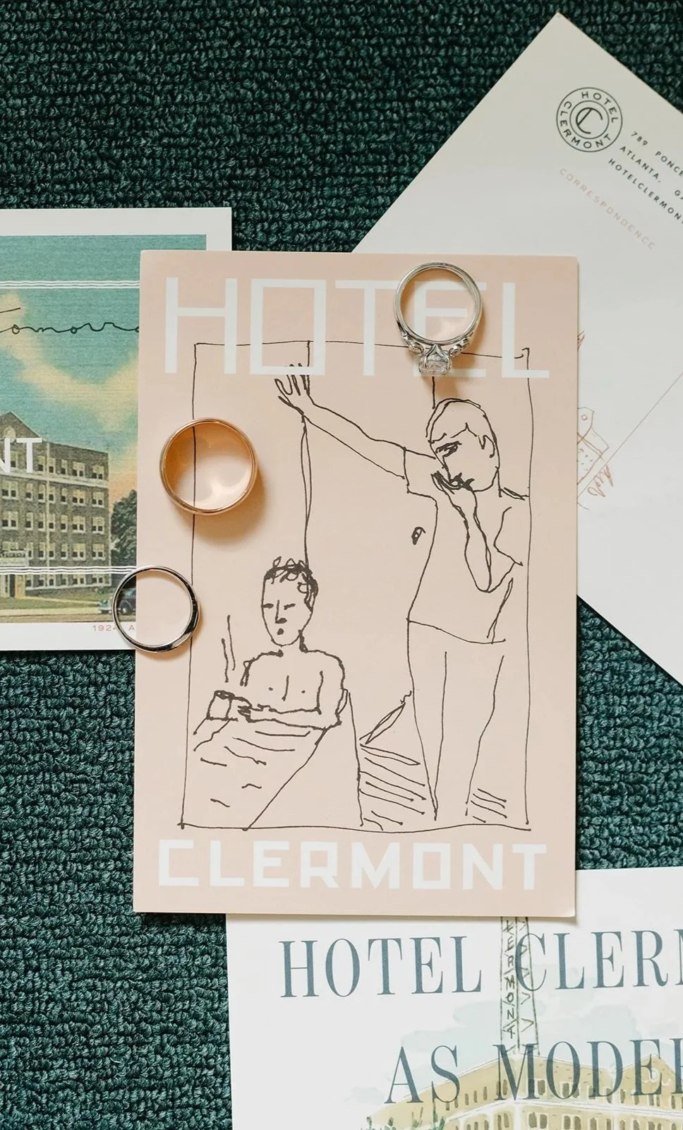 Photograph of a hotel promotional display with rings, a sketch of two people, and hotel branding materials on a textured teal surface.
