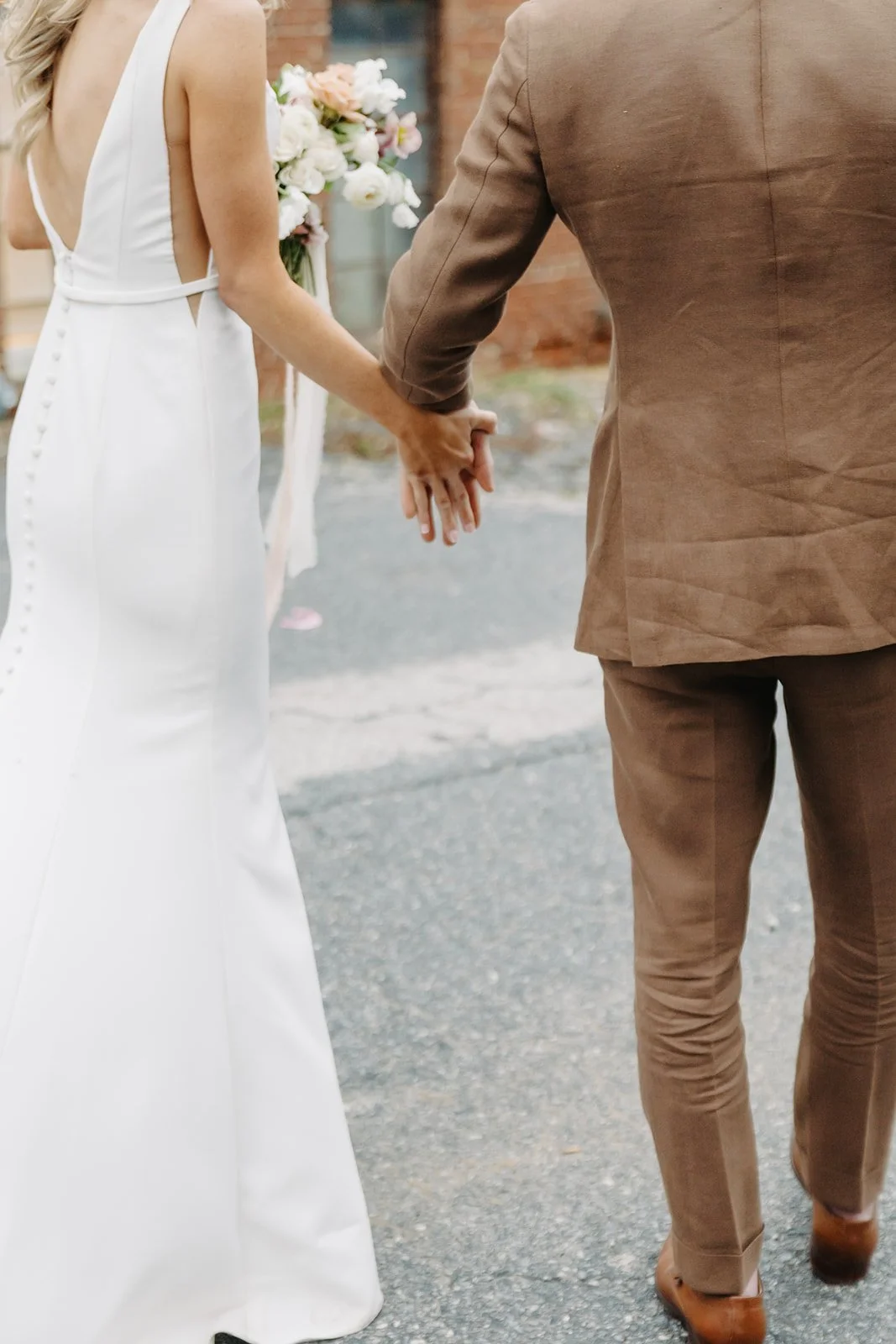 A bride and groom holding hands outdoors during a wedding ceremony.
