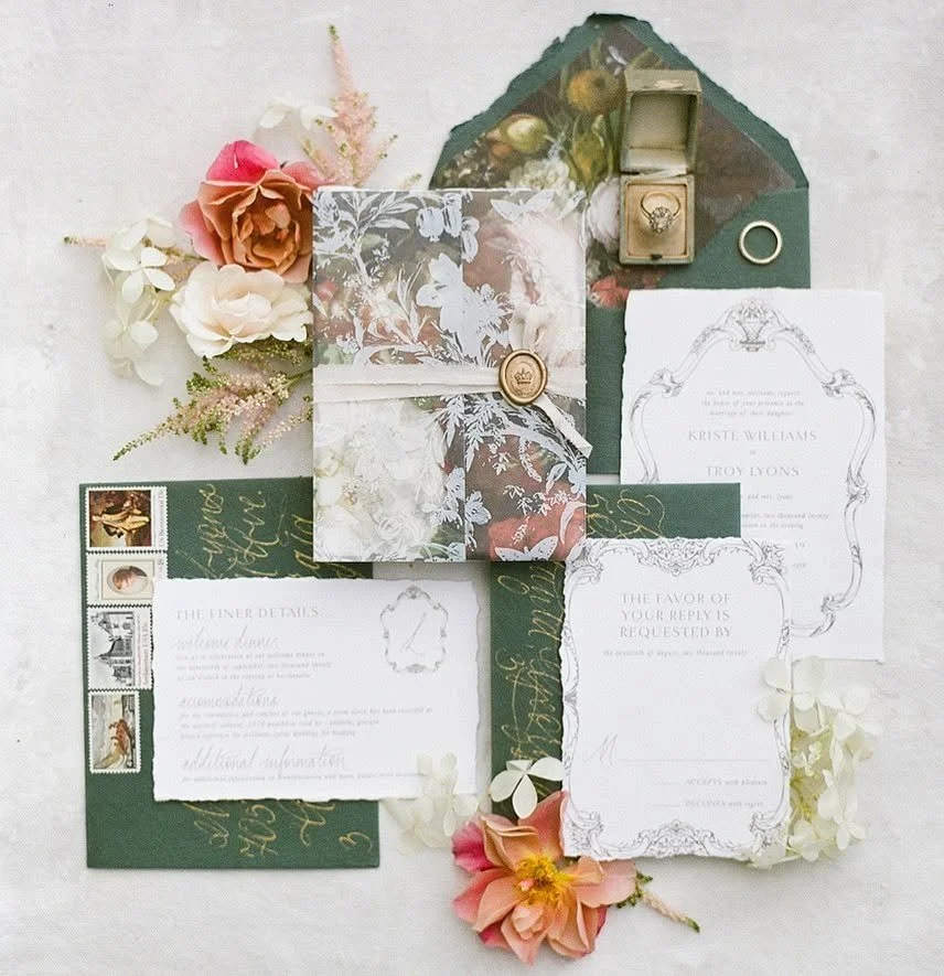 A wedding invitation suite with floral accents, including envelopes, RSVP card, and floral decorative pieces.