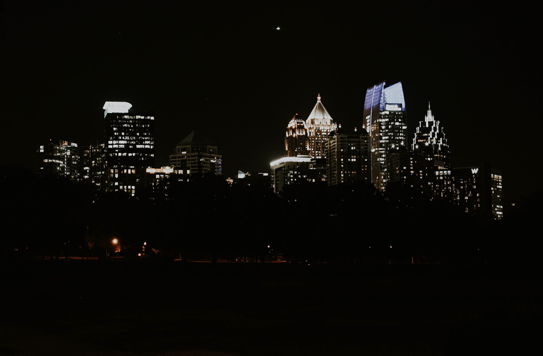 Nighttime city skyline with illuminated skyscrapers against a dark sky.