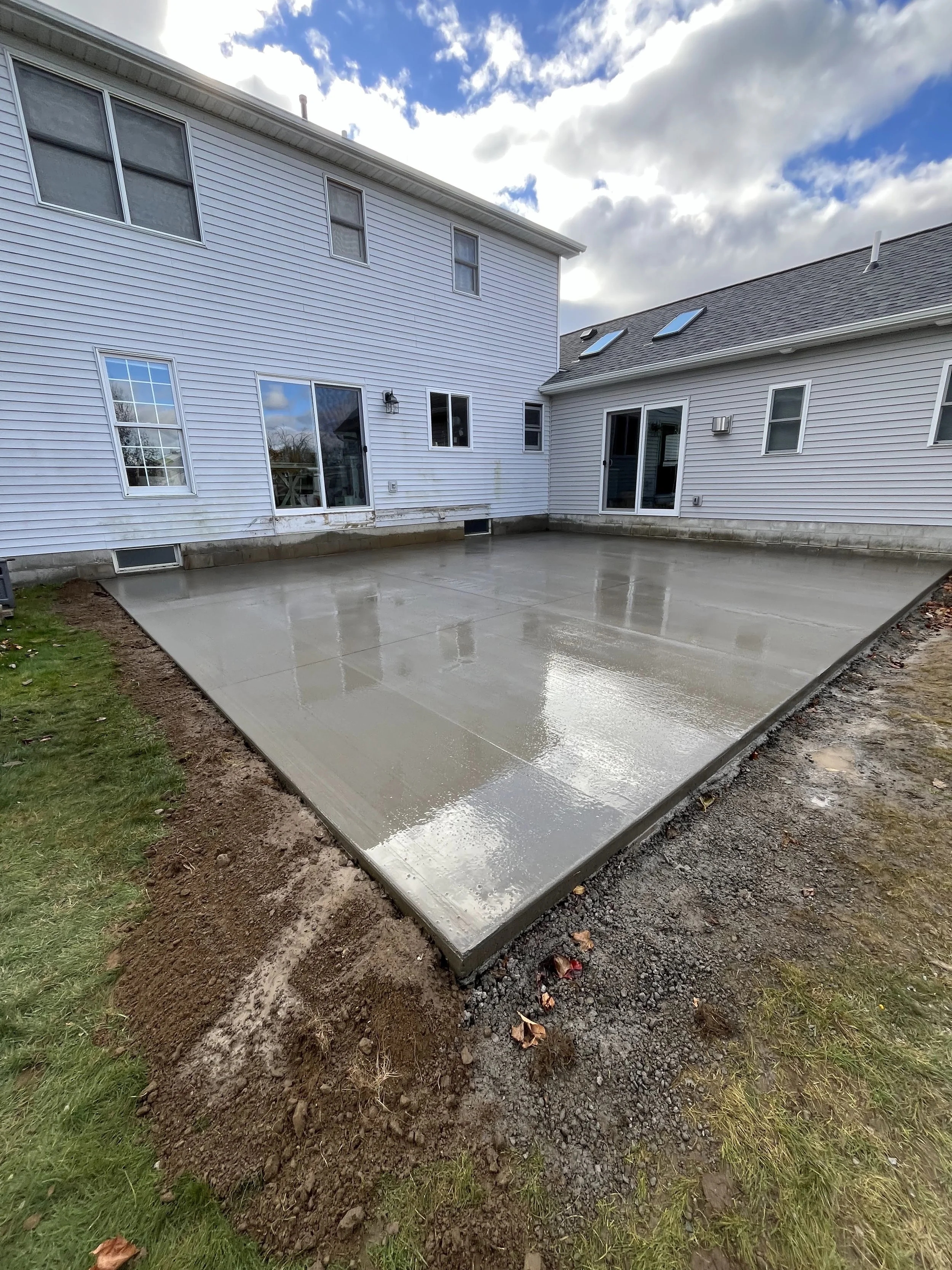 A freshly poured concrete patio in a backyard in Rochester, NY