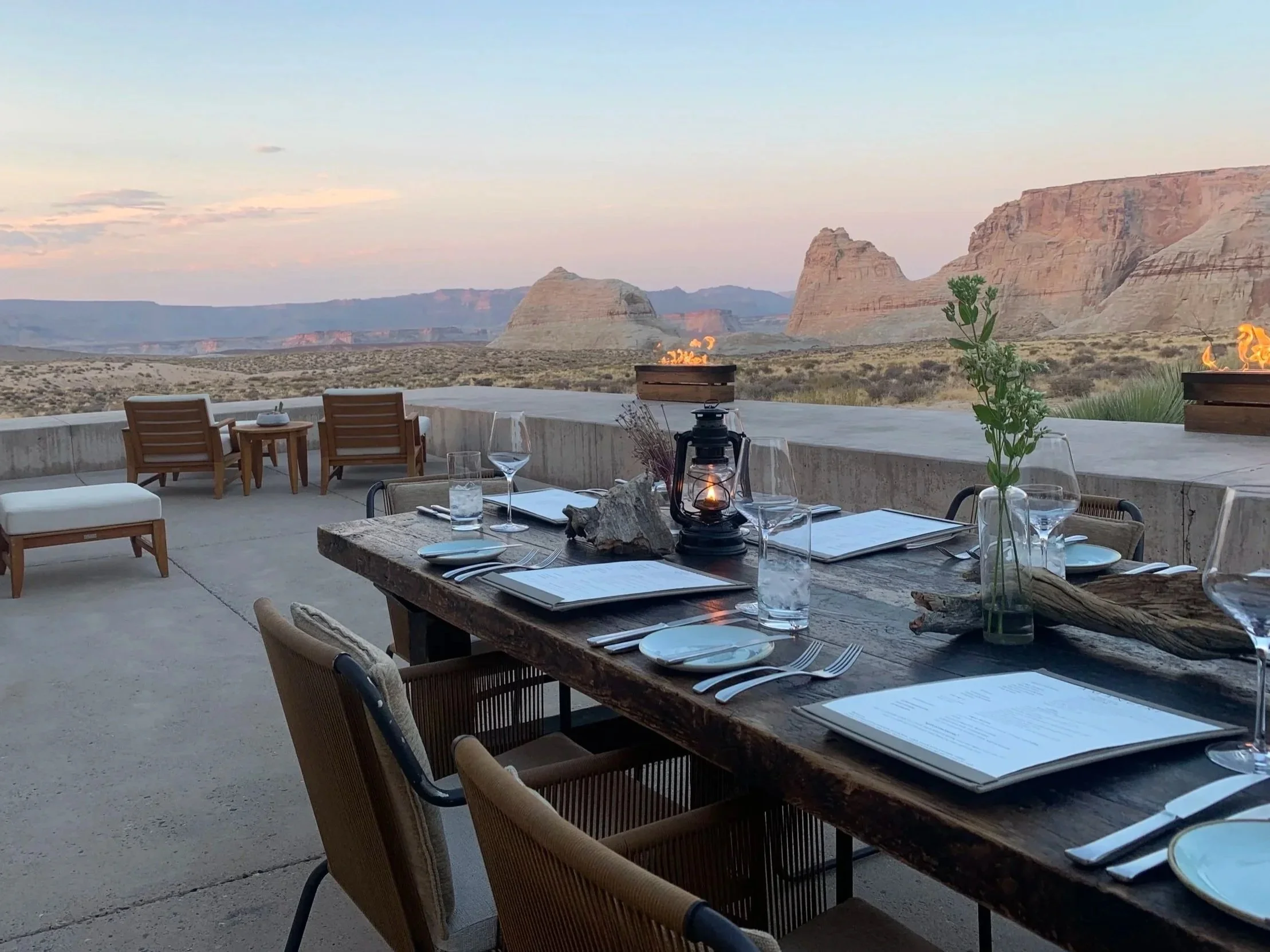 Luxury outdoor dining setting overlooking a dramatic desert landscape at sunset, illustrating destination wedding travel and celebration experiences.