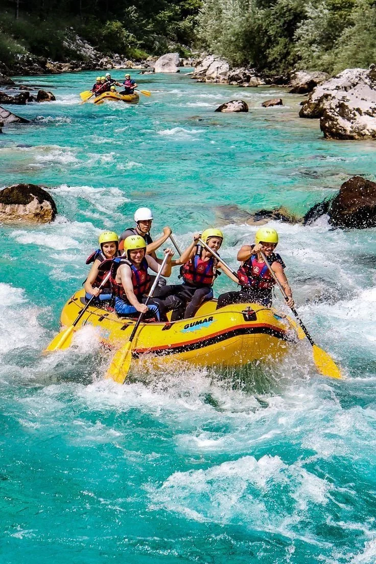Grupo de personas haciendo rafting en un río de aguas turquoise rodeado de vegetación y rocas.