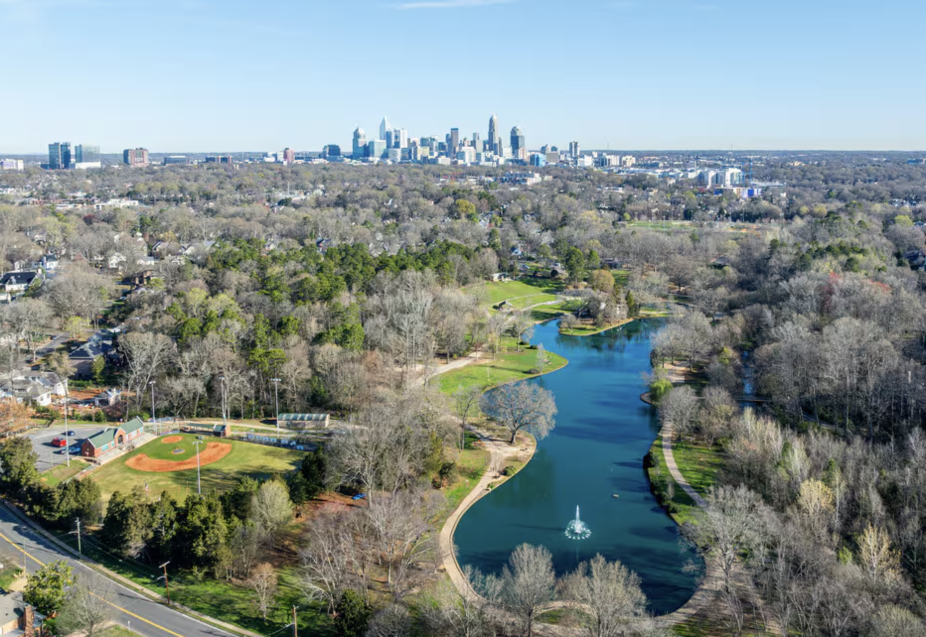 Aerial view of a city skyline with a river and park in the foreground.