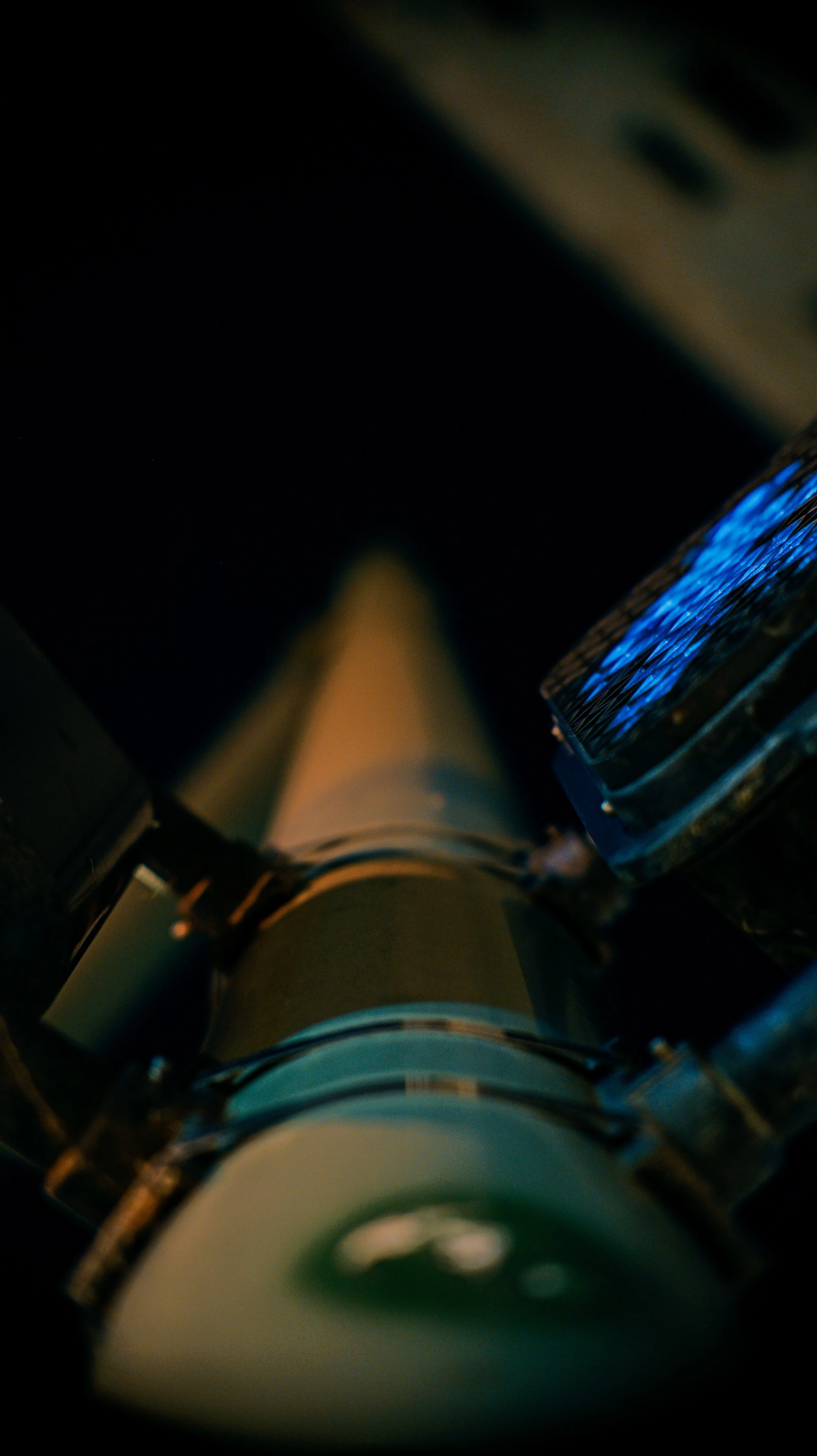 A telescope viewing a starry sky at night with a focus on the eyepiece and some blue lights or reflections.
