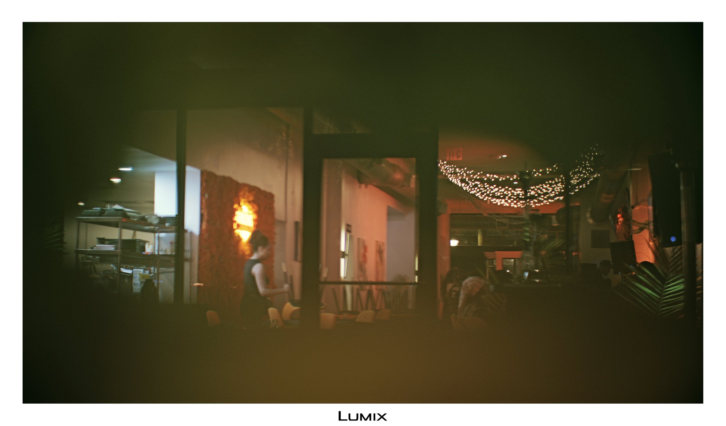 Indoor scene at night with hanging string lights, a person standing and another sitting at a table, and various decorations and furniture.