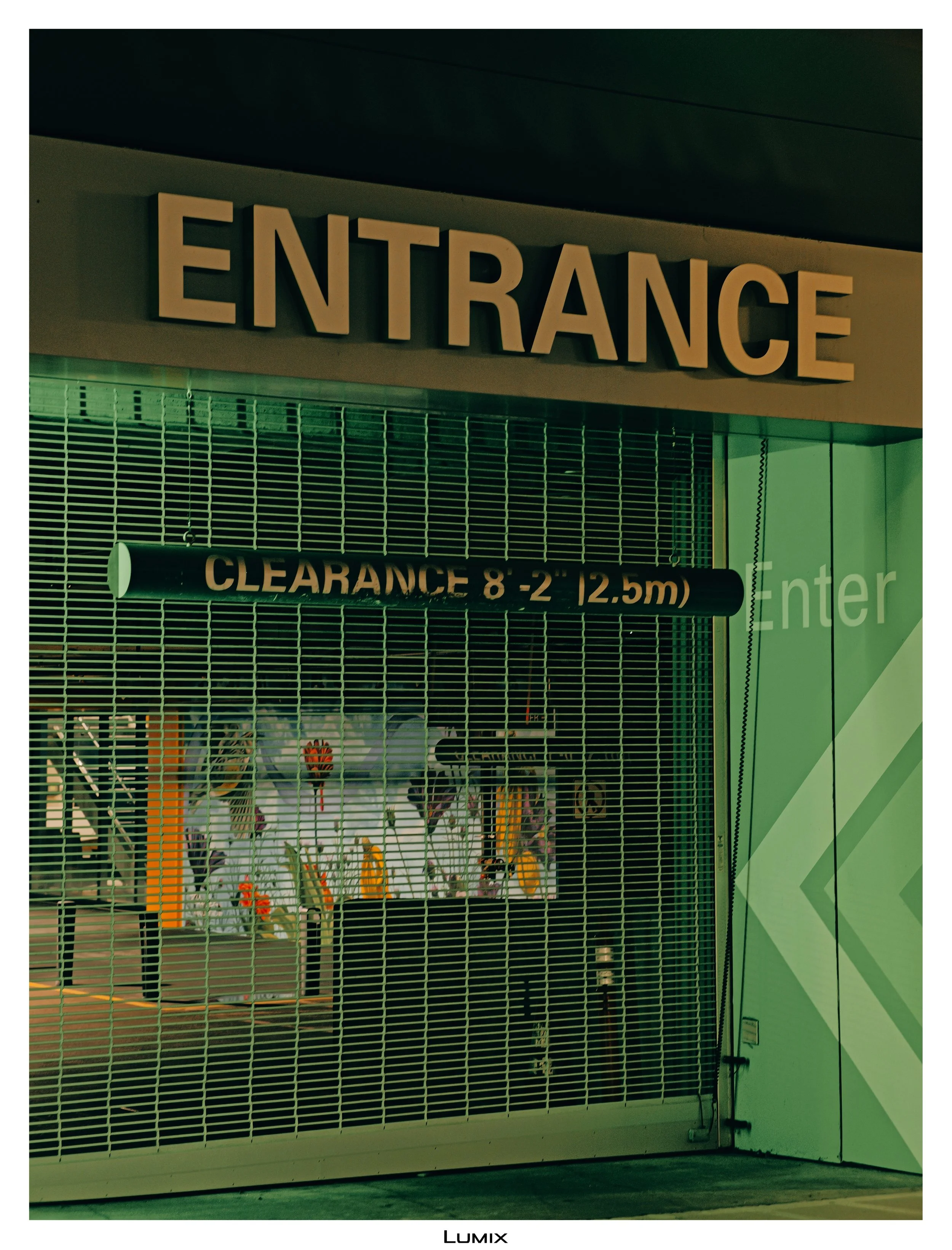 Closed entrance with a metal security shutter and a sign indicating clearance height of 8 to 12.5 meters, possibly in a parking garage or commercial building.