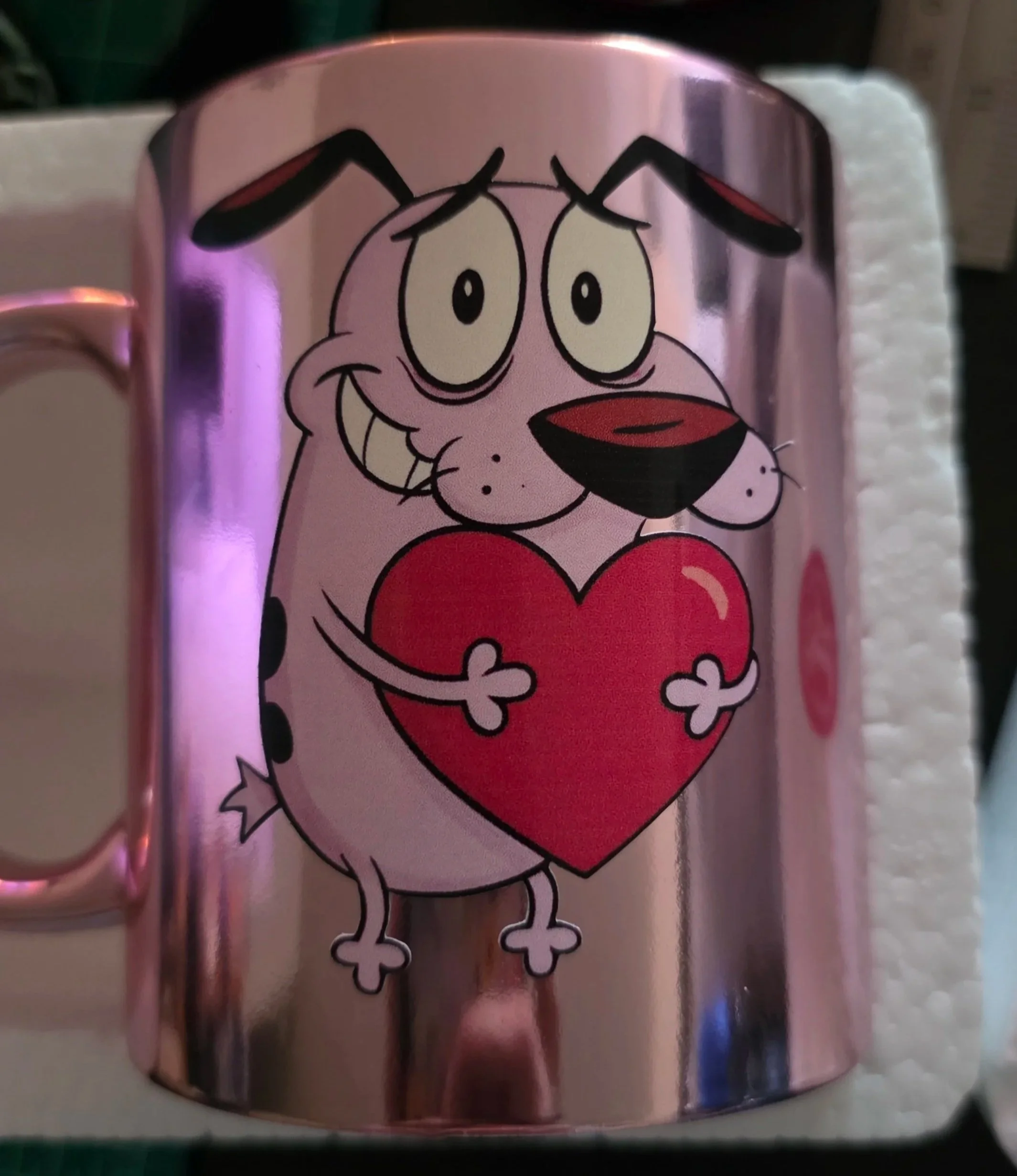 A metallic mug with a cartoon drawing of a dog holding a large red heart.