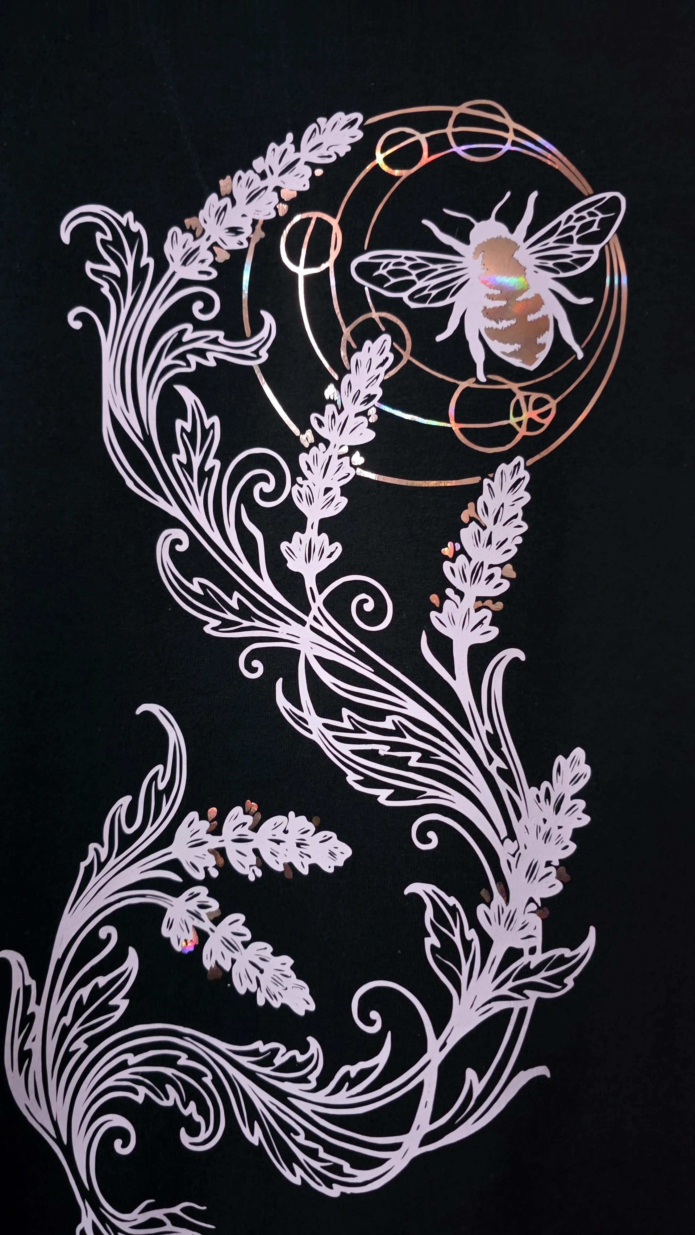 A decorative design featuring a bee with detailed wings and body, surrounded by swirling floral and botanical patterns, on a black background.