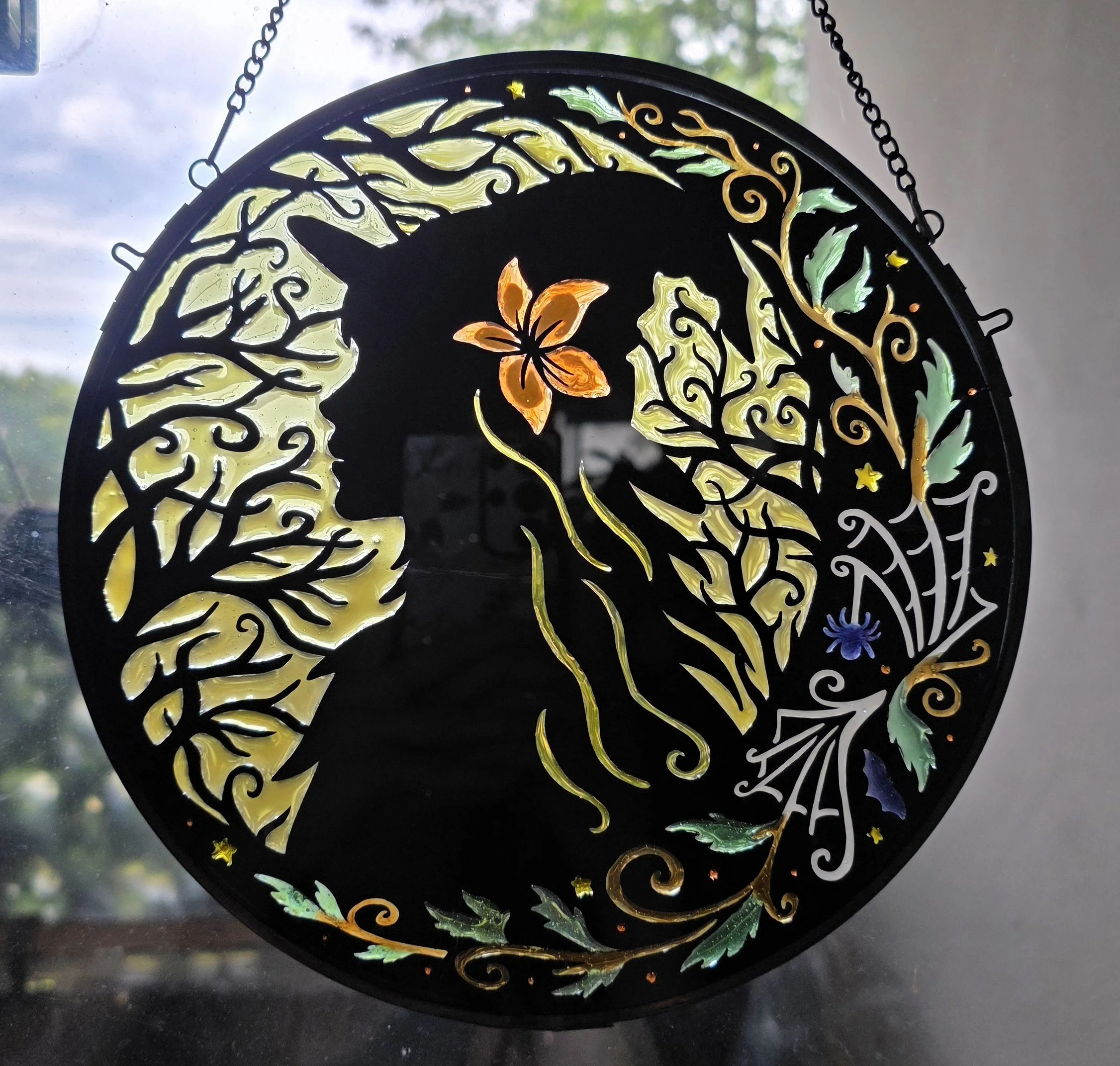 Close-up of decorative stained glass panel featuring a butterfly, floral patterns, and leafy scrolls with a black background