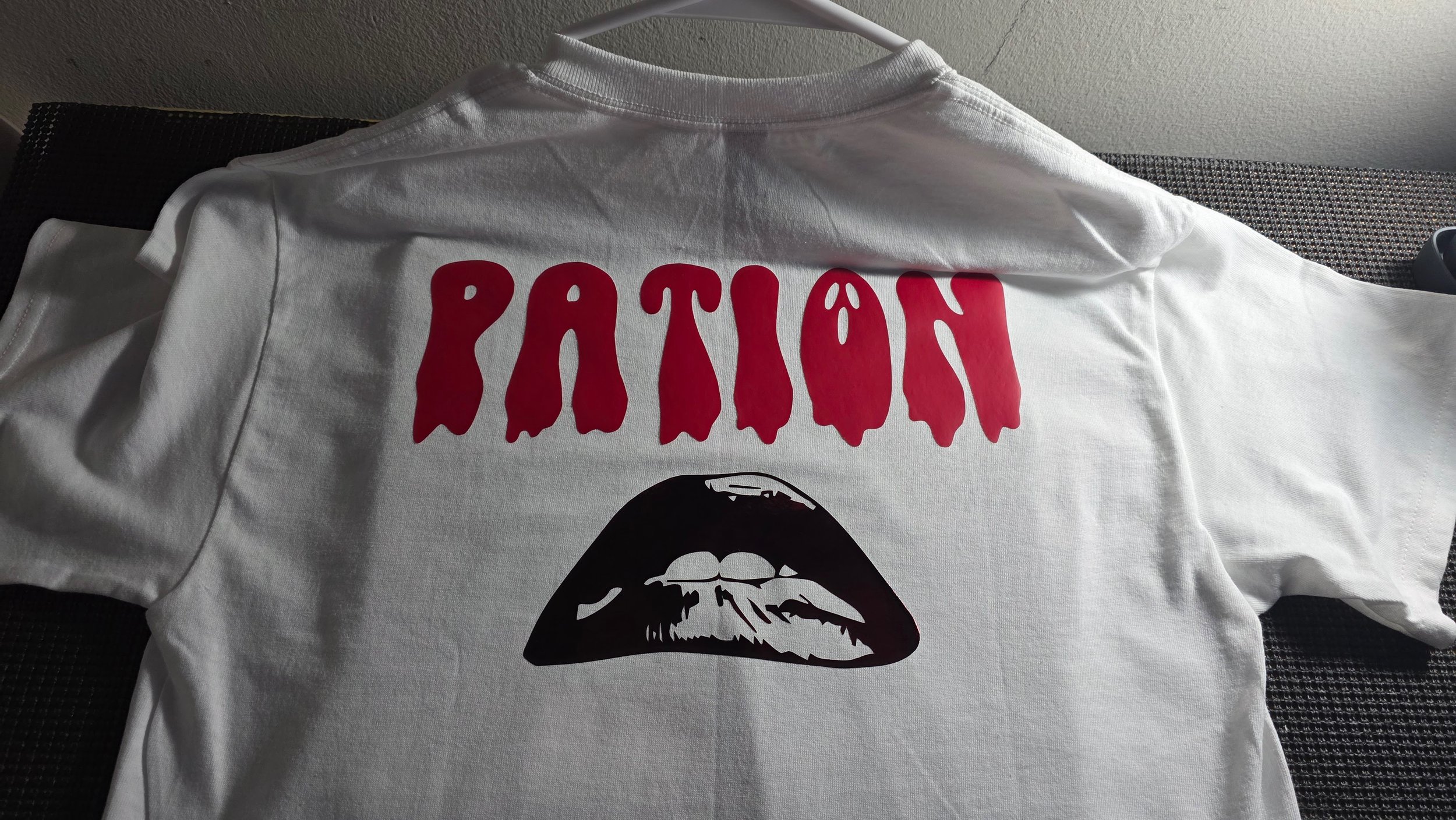 A white T-shirt with red text that reads 'PATION' and a graphic of Rocky Horror Picture Show lips underneath.