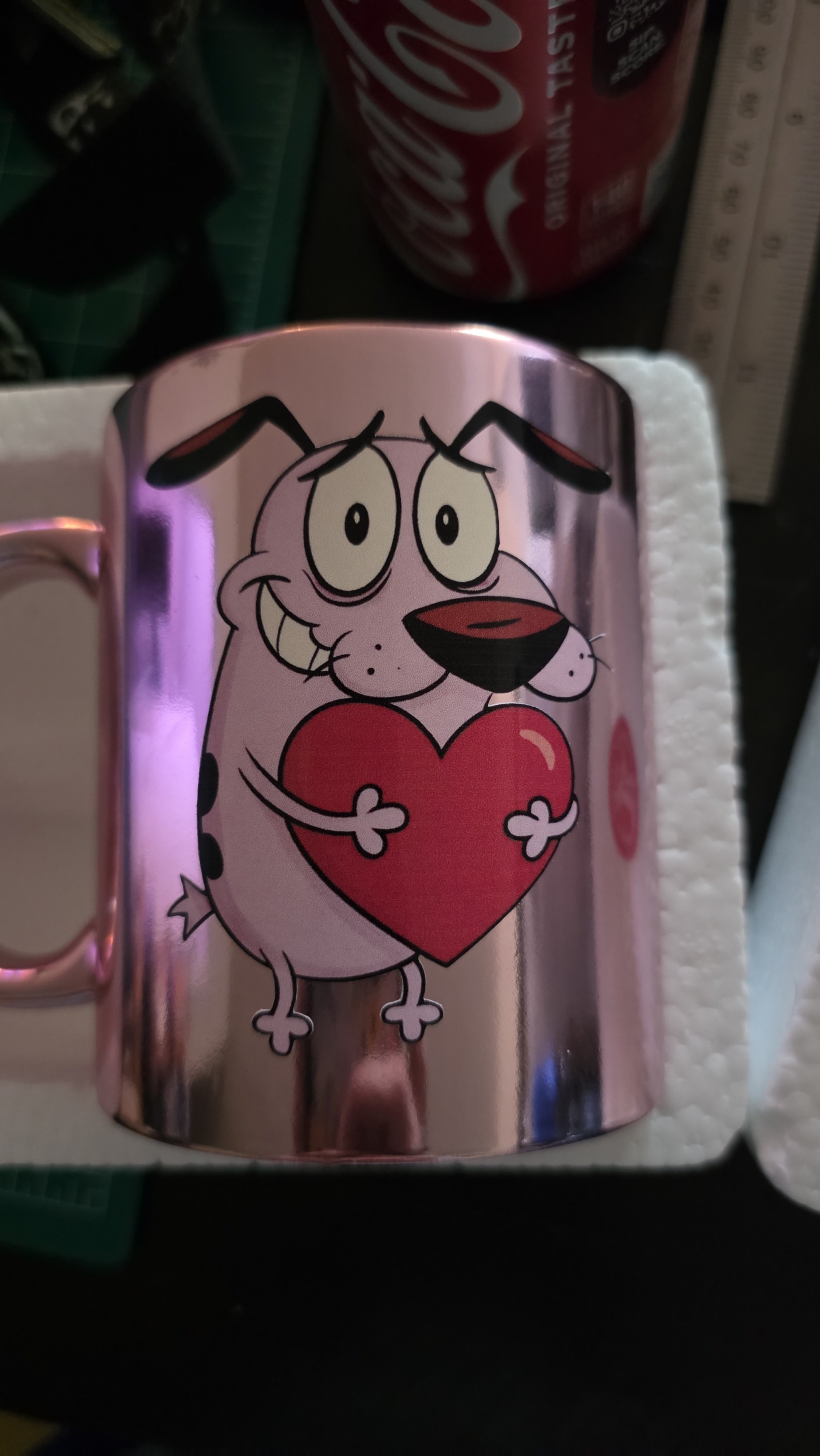 A metallic mug with a cartoon drawing of a dog holding a large red heart.
