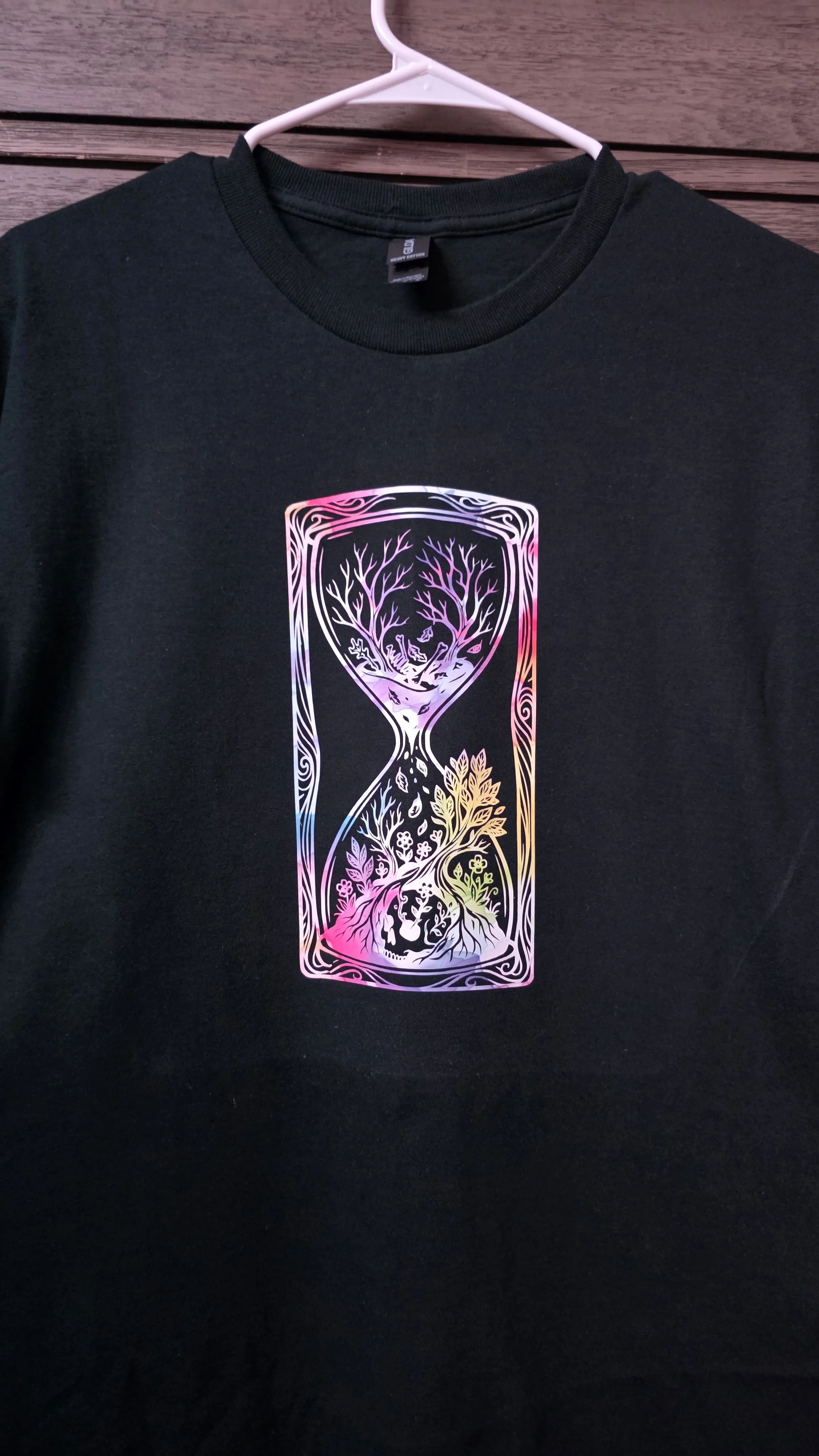 Black T-shirt with a colorful, holographic-style design of an hourglass filled with trees and nature scenes.