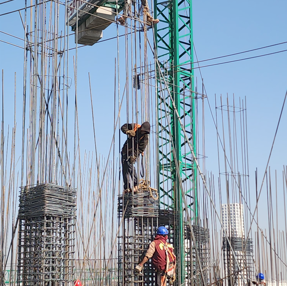 Construcción de un edificio con trabajadores instalando varillas de acero y estructura de acero en un sitio en construcción.