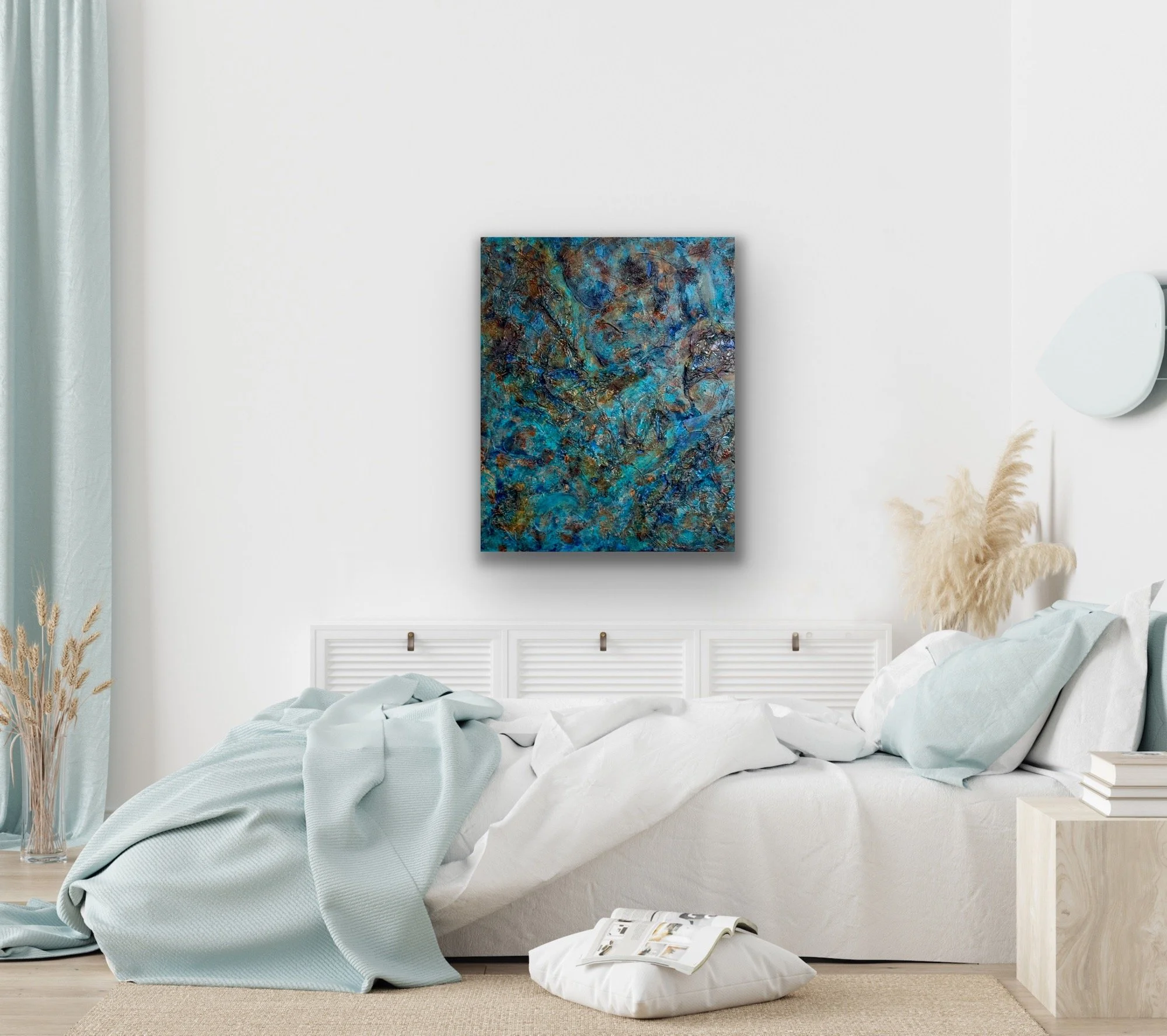 Unmade bed with white bedding and an open magazine on a floor cushion, in a bright bedroom with light-colored decor, abstract artwork on the wall, and soft natural lighting.