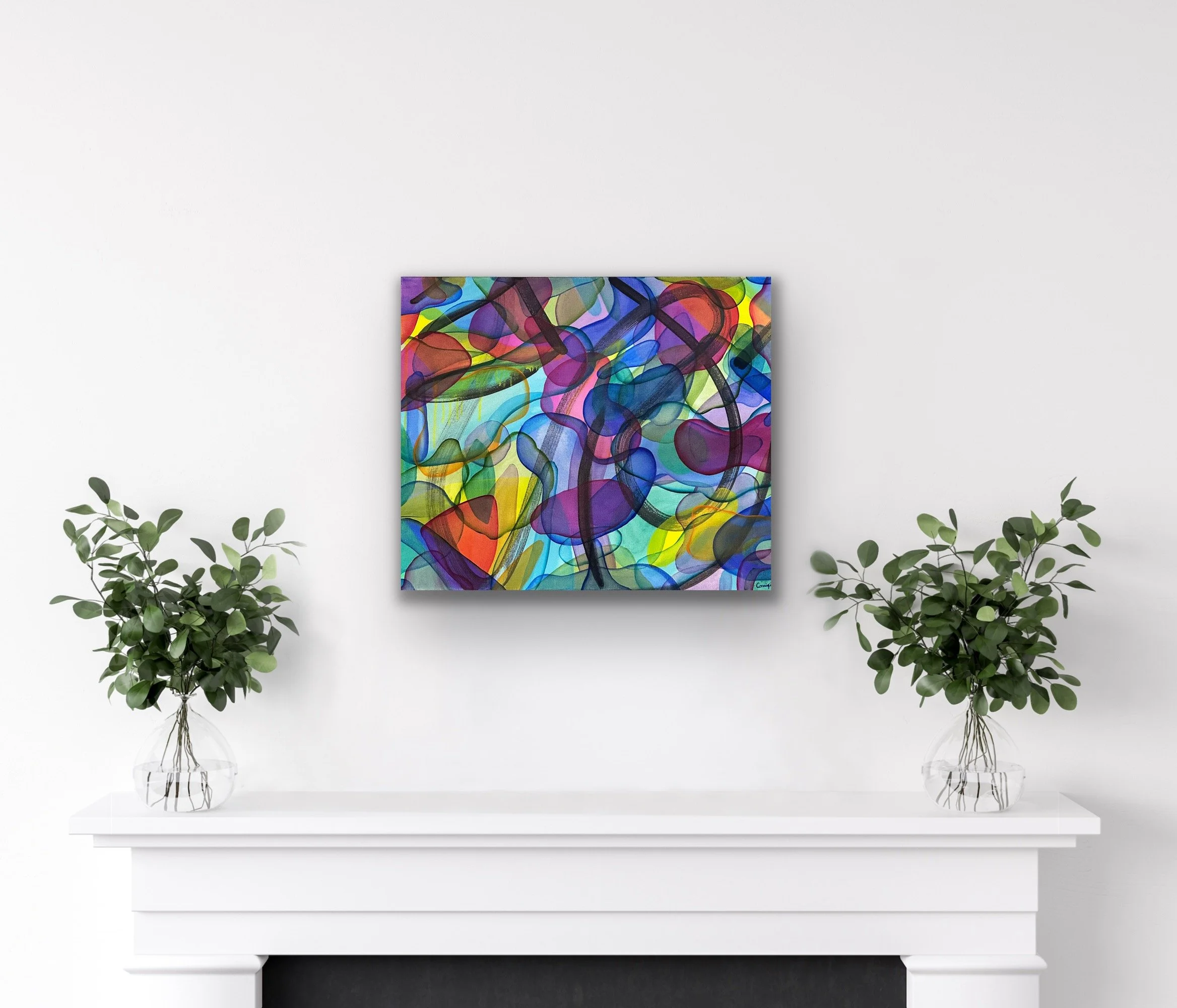 A colorful abstract painting on the wall above a white mantelpiece. Two glass vases with green leafy plants are placed on either side of the mantel on a white surface. The background wall is white, and the overall setting has a minimalist aesthetic.