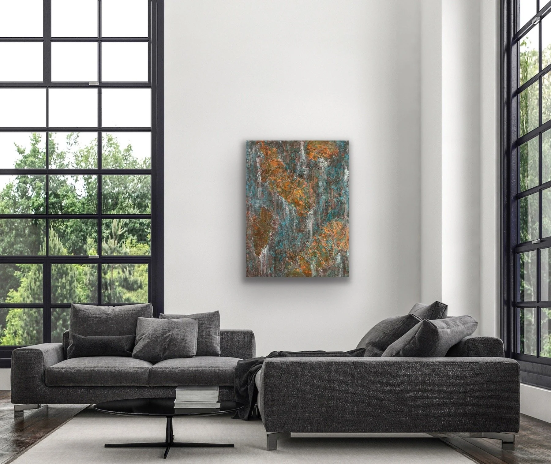 Modern living room with large black-framed windows, a gray sectional sofa with cushions, a black coffee table with books, and an abstract painting on a white wall.