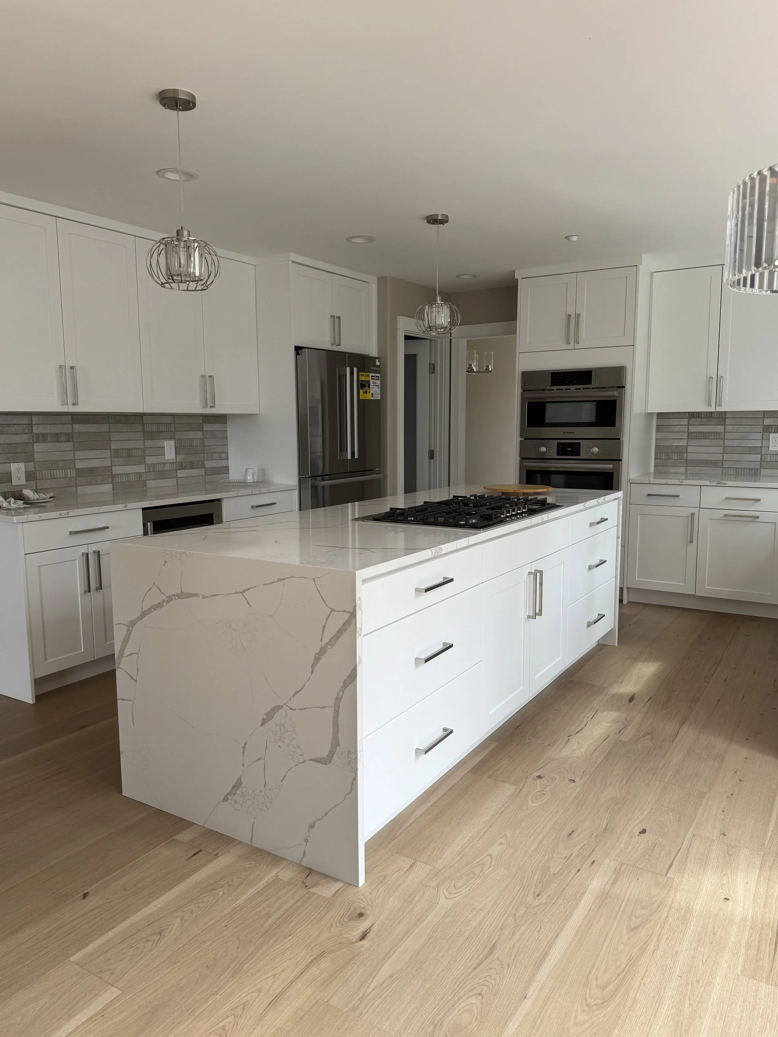 Luxury kitchen island with quartz waterfall edge and built-in gas cooktop, custom-built by high end general contractor Tennison Design Build