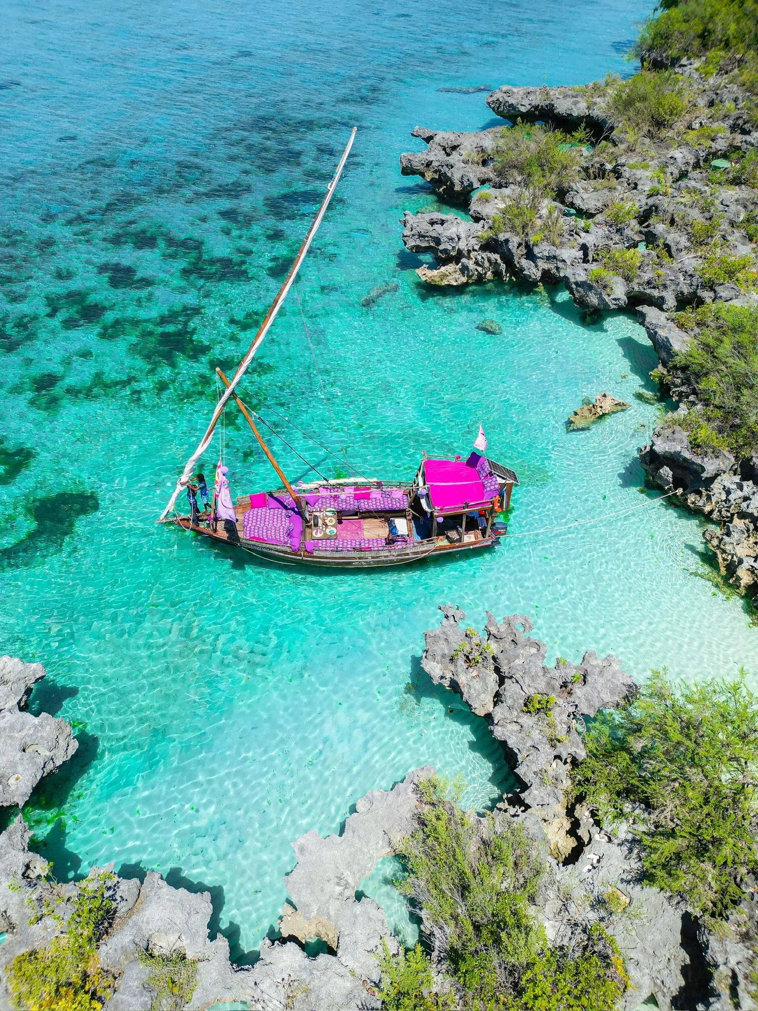 A tropical scene with clear turquoise water surrounded by rocky cliffs and green vegetation.