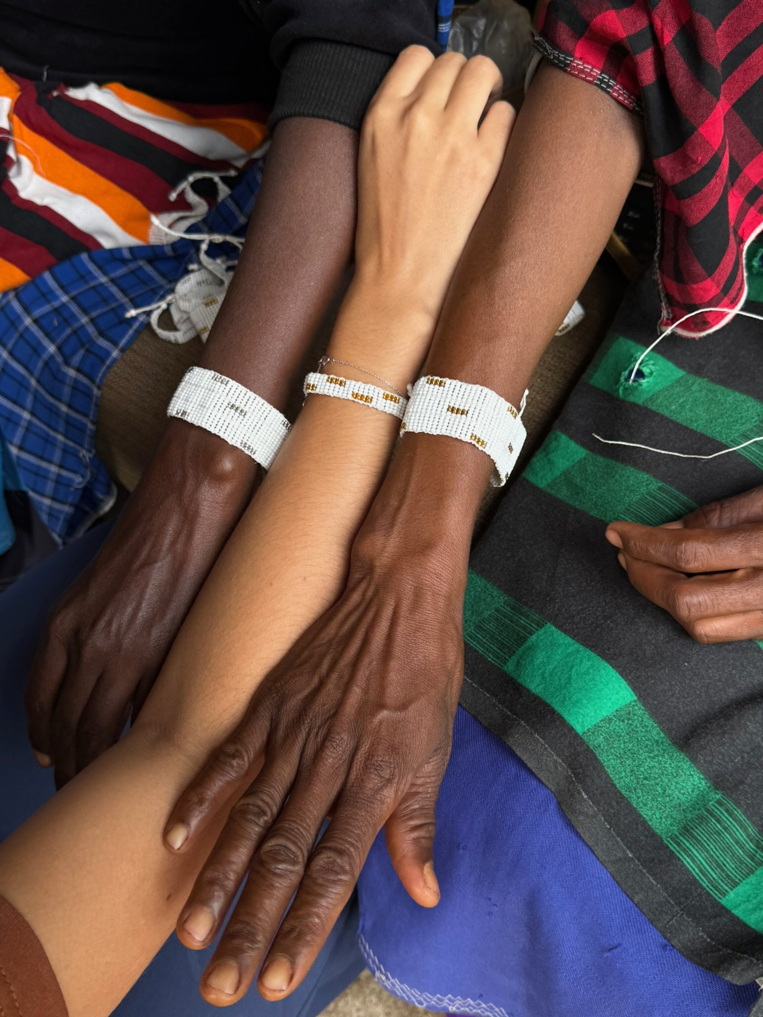 Multiple hands of different skin tones placed on top of each other, symbolizing unity and diversity.