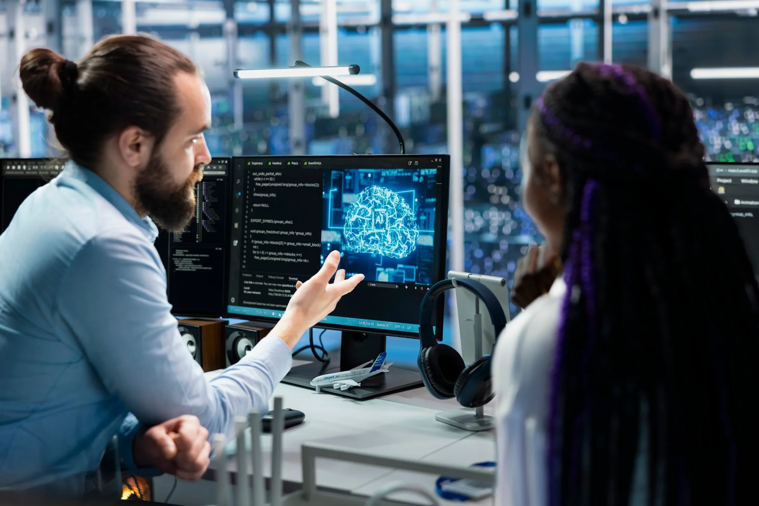 Two scientists in a laboratory working on computer screens displaying a digital brain and coding, with a modern cityscape visible through the windows behind them.