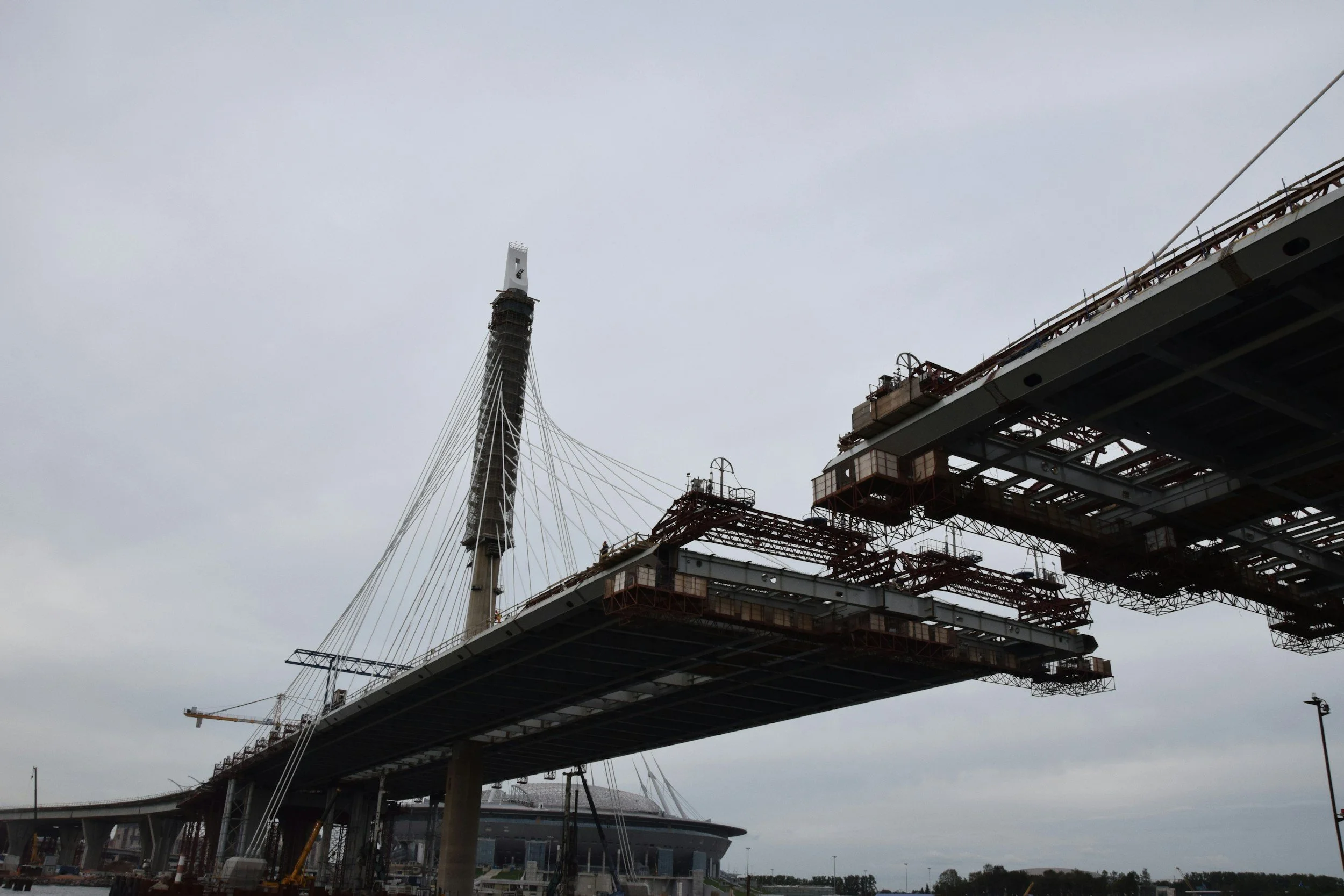Under construction bridge with a tower and cables, overcast sky.