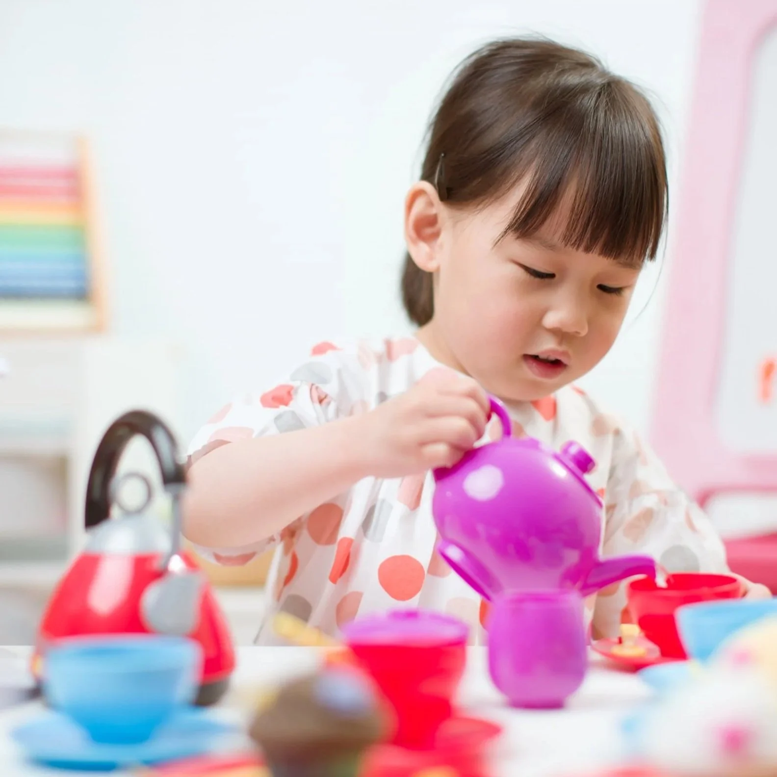 Child playing with a toy tea set during a Learn to Play therapy session