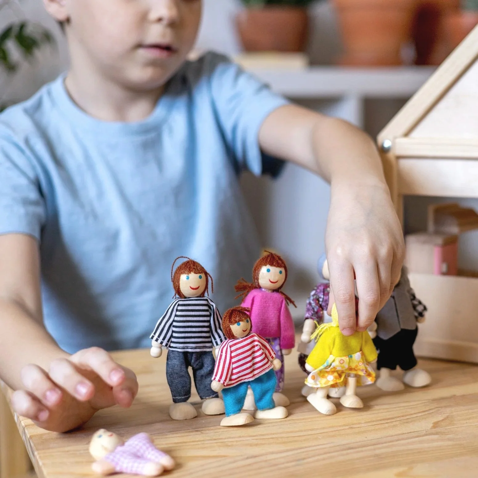 Child arranging doll family figures during a humanistic play therapy session