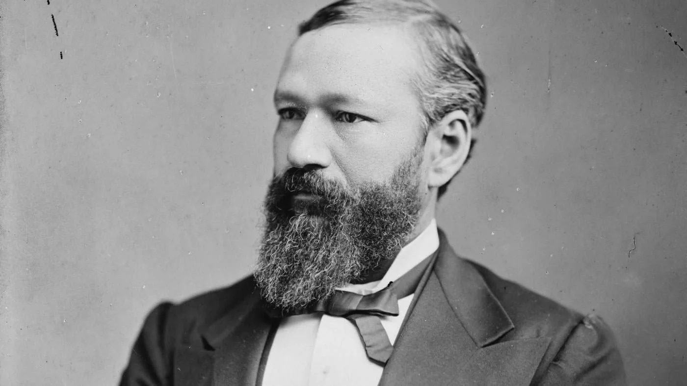 Black and white portrait of Abraham Lincoln with a beard, wearing a suit and bow tie.