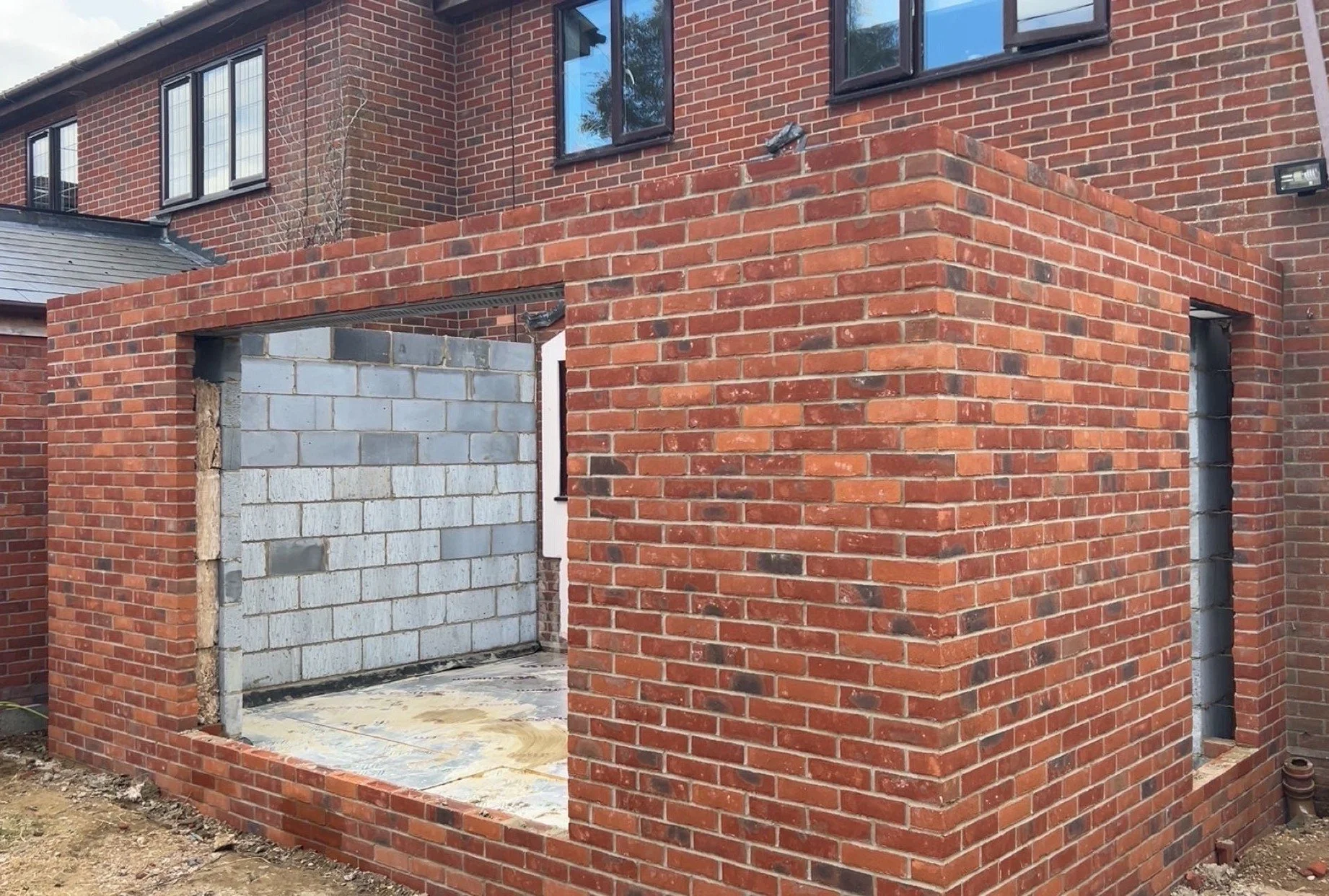 Construction site with brick walls and an open wall showing unfinished interior with concrete blocks